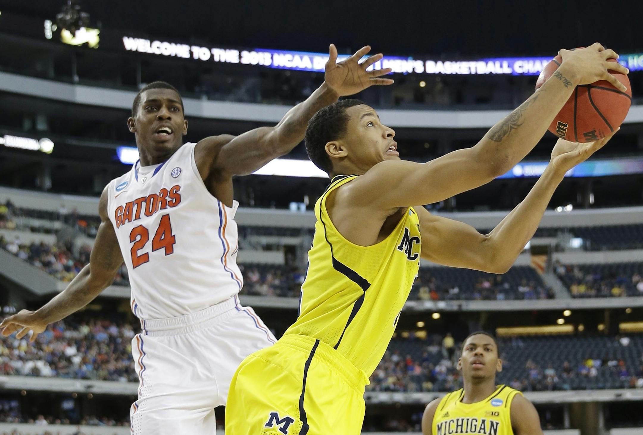 Michigan's Trey Burke (3) grabs a rebound as Florida's Casey Prather (24) defends during the second half of a regional final game in the NCAA college basketball tournament, Sunday, March 31, 2013, in Arlington, Texas. (AP Photo/David J. Phillip)
