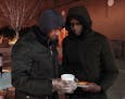 Abdirahman Mukhtar spoke with a man as he and Abdullahi Farah, left, gave out pizza and tea to young people from a stand Friday in the Cedar-Riverside