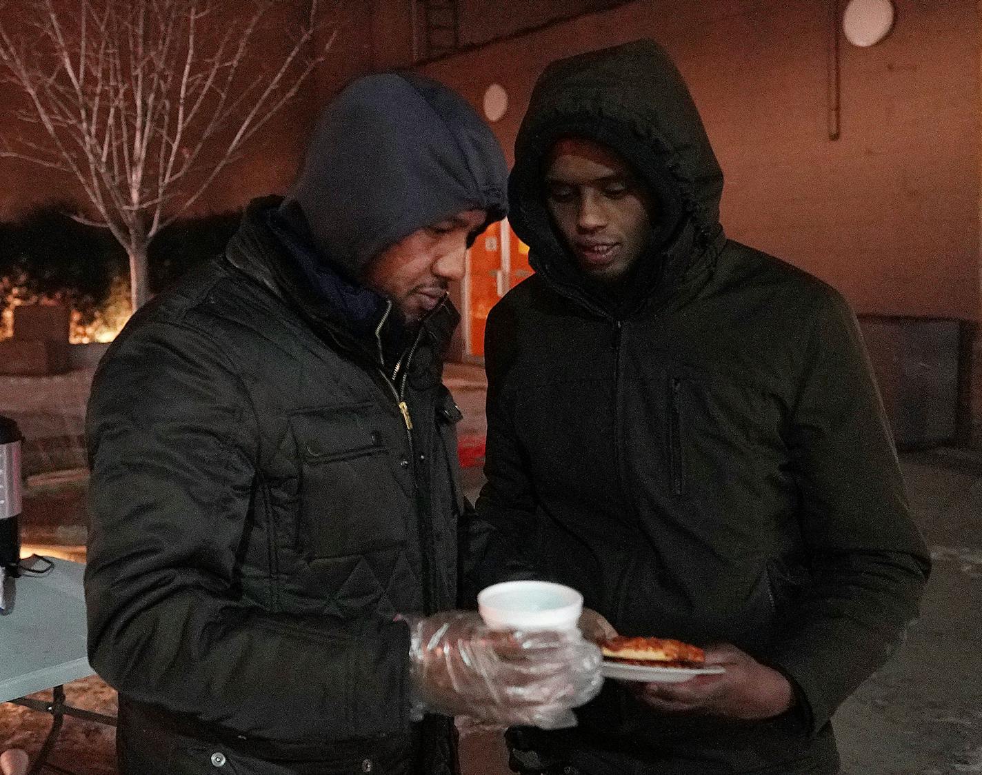 Abdirahman Mukhtar spoke with a man as he and Abdullahi Farah, left, gave out pizza and tea to young people from a stand Friday in the Cedar-Riverside neighborhood. ] ANTHONY SOUFFLE &#x2022; anthony.souffle@startribune.com A group of Somali volunteers including Abdirahman Mukhtar, Abdullahi Farah, and Mahdi Abdi gave out pizza and tea to young people from a stand Friday, Dec. 28, 2018 in the Cedar-Riverside neighborhood of Minneapolis. The men hope by connecting with youth and engaging them in