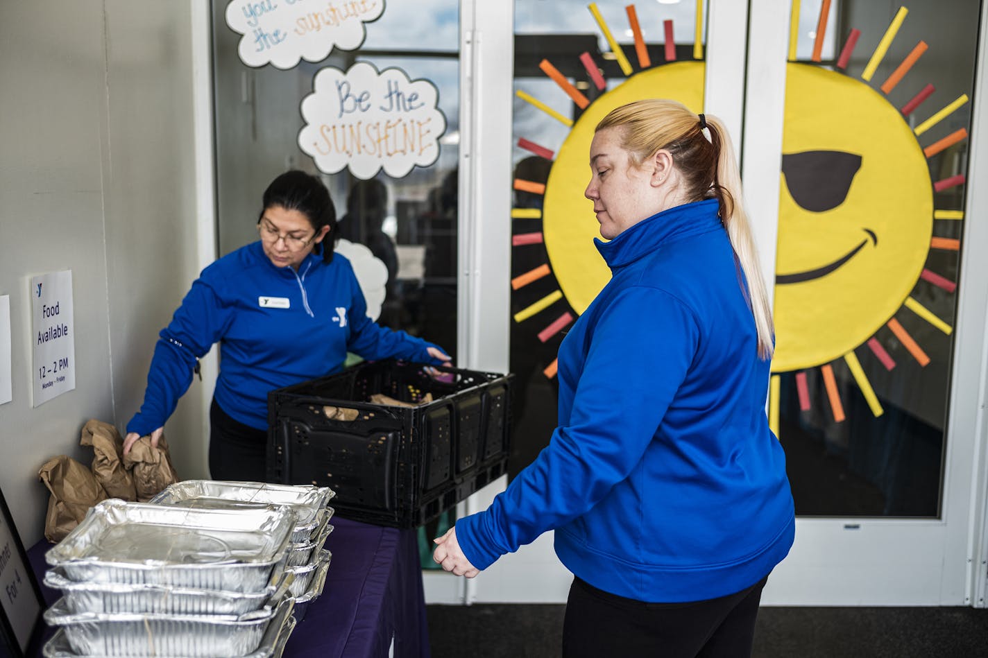 At the St. Paul Eastside YMCA, manager Courtney Troyer, left, and employee Mary Kelly put out parmesan chicken dinners on April 13. Meals are distributed 12-2PM Monday through Friday throughout the metro.