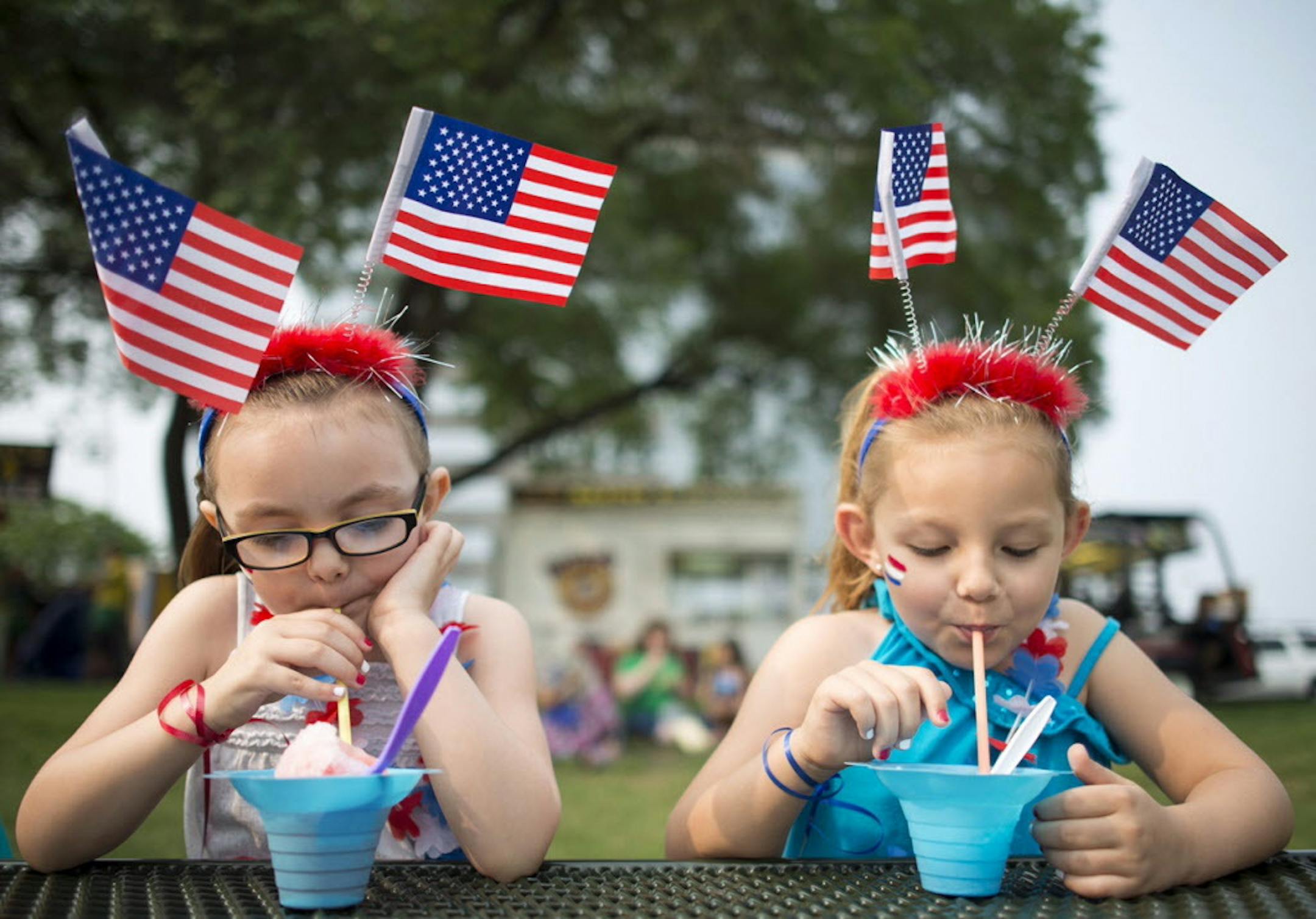 Sisters Alyksa Shaw, 5, and Ashlyn, 6, of Burnsville, enjoyed shaved ice while donning patriotic head gear at Summer Fete at Normandale Lake Park in Bloomington on Friday afternoon.