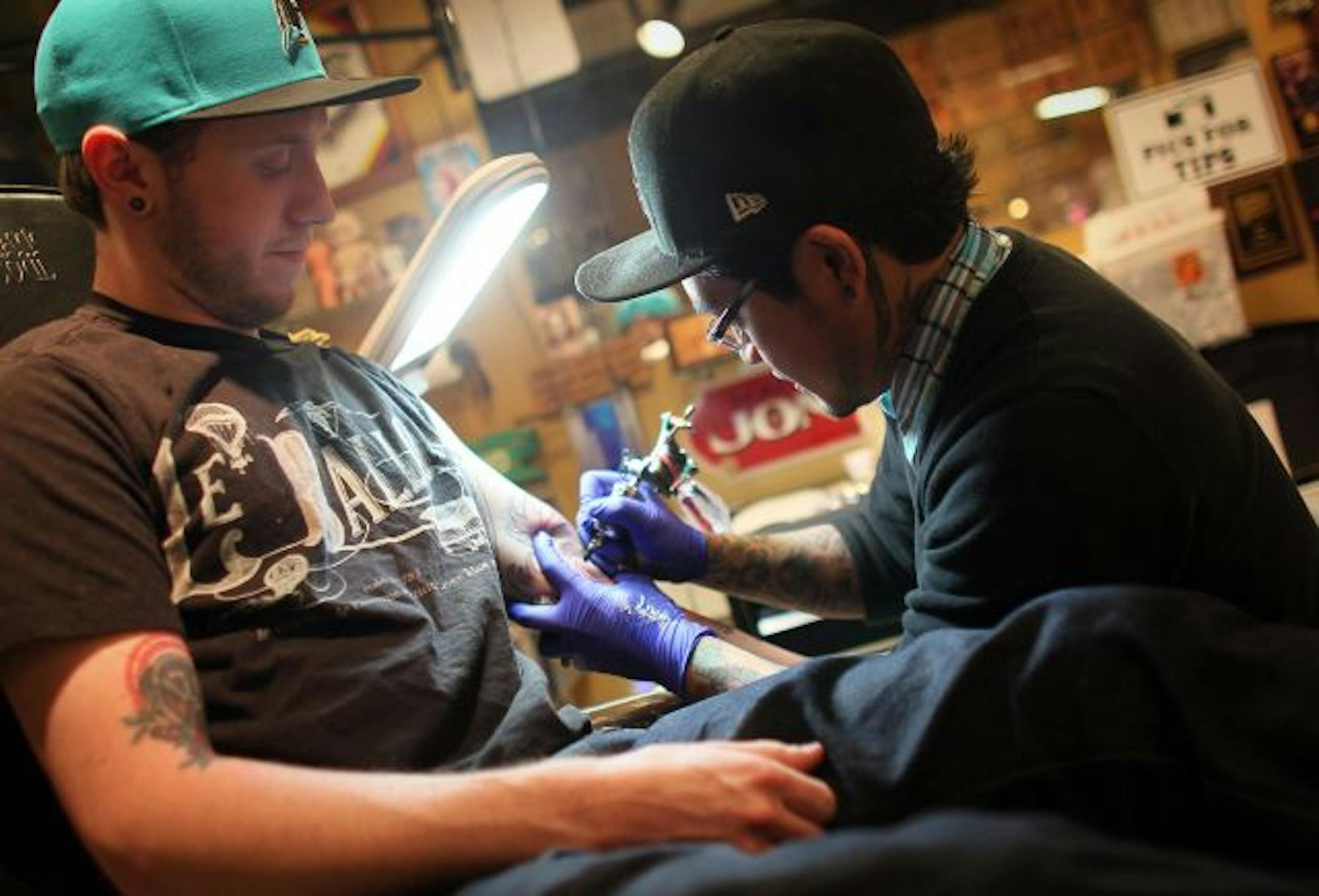 Jon Boy, owner of Dinkytown Tattoo in Minneapolis, tattooed 23-year-old Ian Cosgrove's arm Monday night. New safety measures will allow people who get tattoos to donate blood without having to wait a year. Blood centers see the change as a way to help establish young adults as donors.