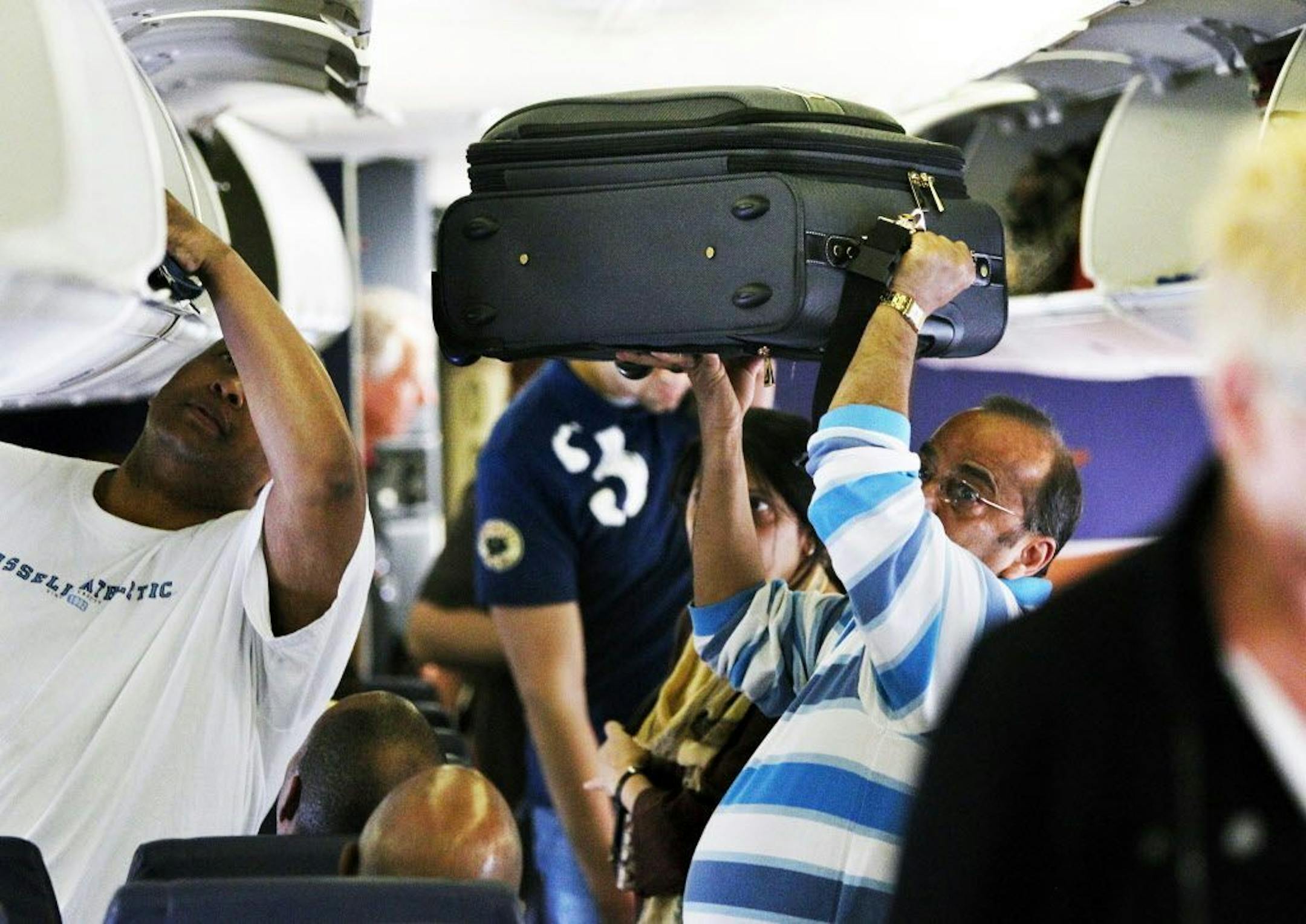 A Southwest Airline passenger lifts his luggage into the air while looking for a storage spot in the overhead compartments before a flight from Midway Airport in Chicago to Cleveland, Ohio, April 2, 2010.