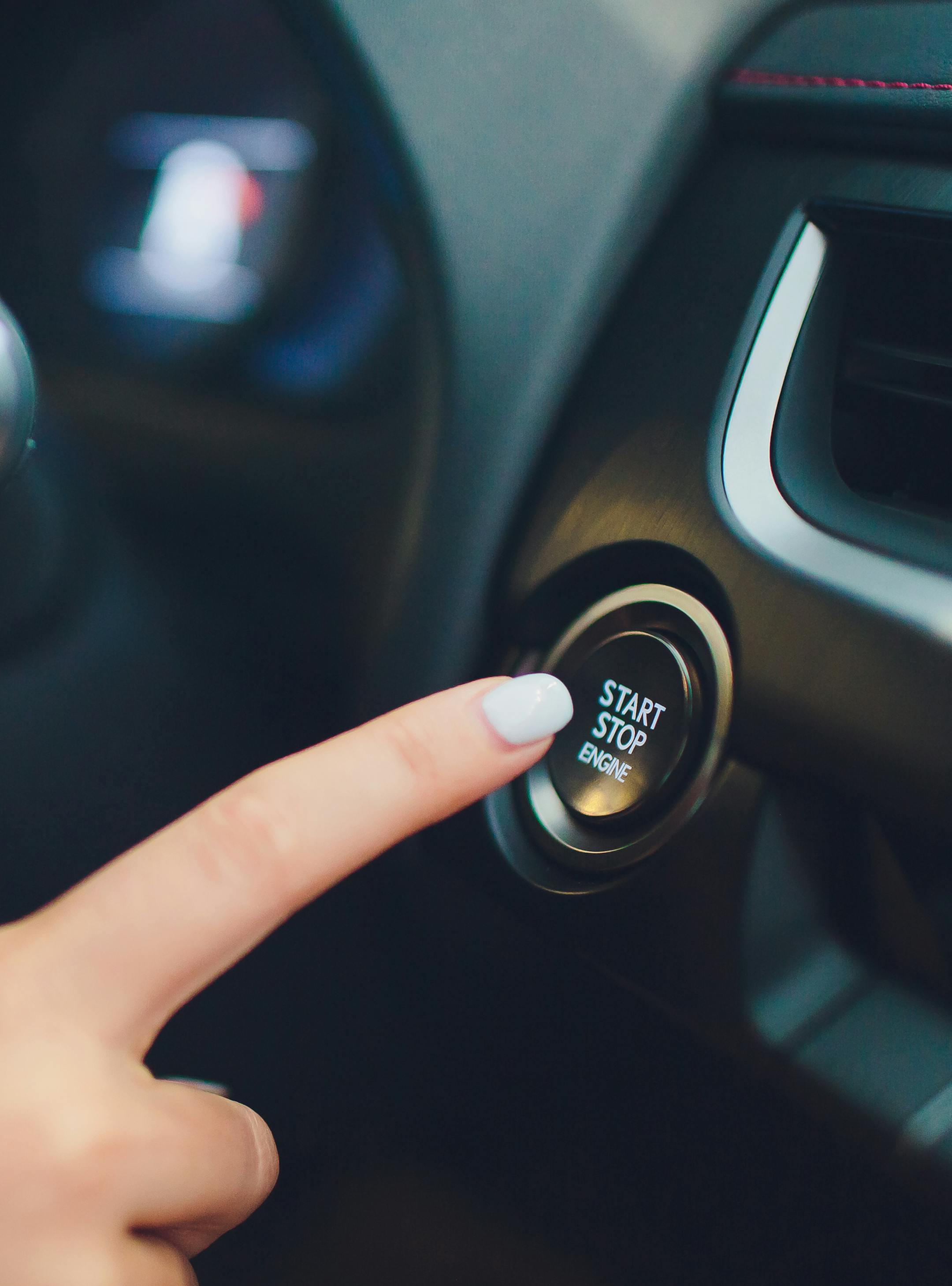 Car driver starting the engine keyless. Black. female hand