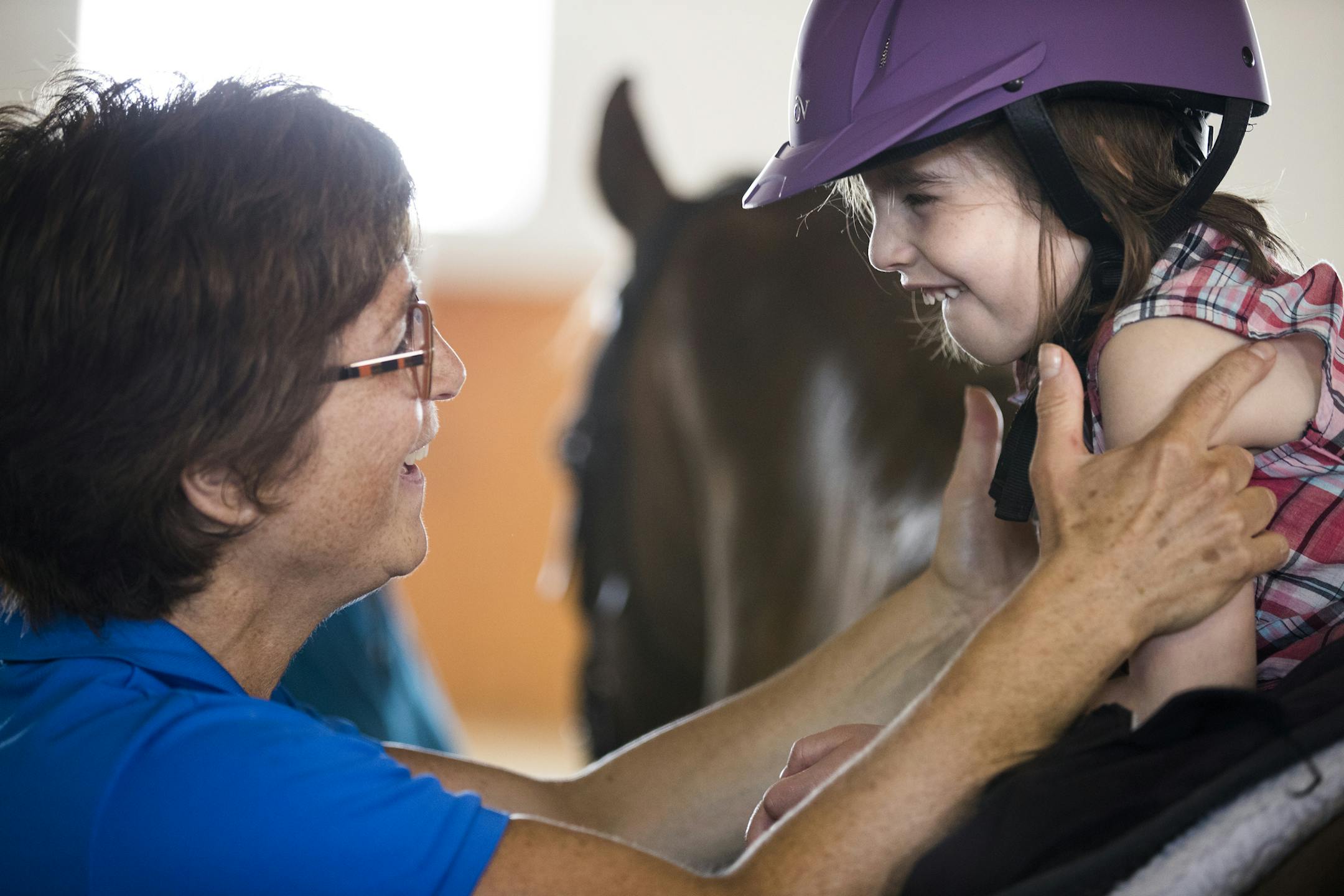 Ellie Soderberg, 4, participates in an occupational therapy session with Janet Weisberg, an occupational therapist and the executive director of Hold Your Horses in Maple Plain. ] (Leila Navidi/Star Tribune) leila.navidi@startribune.com BACKGROUND INFORMATION: Wednesday, July 13, 2016 in Maple Plain. Hold Your Horses, a horse therapy program in Maple Plain, is moving barns in August. After thinking they would lose the whole program, a landowner offered a half sale/donation that will allow the pr