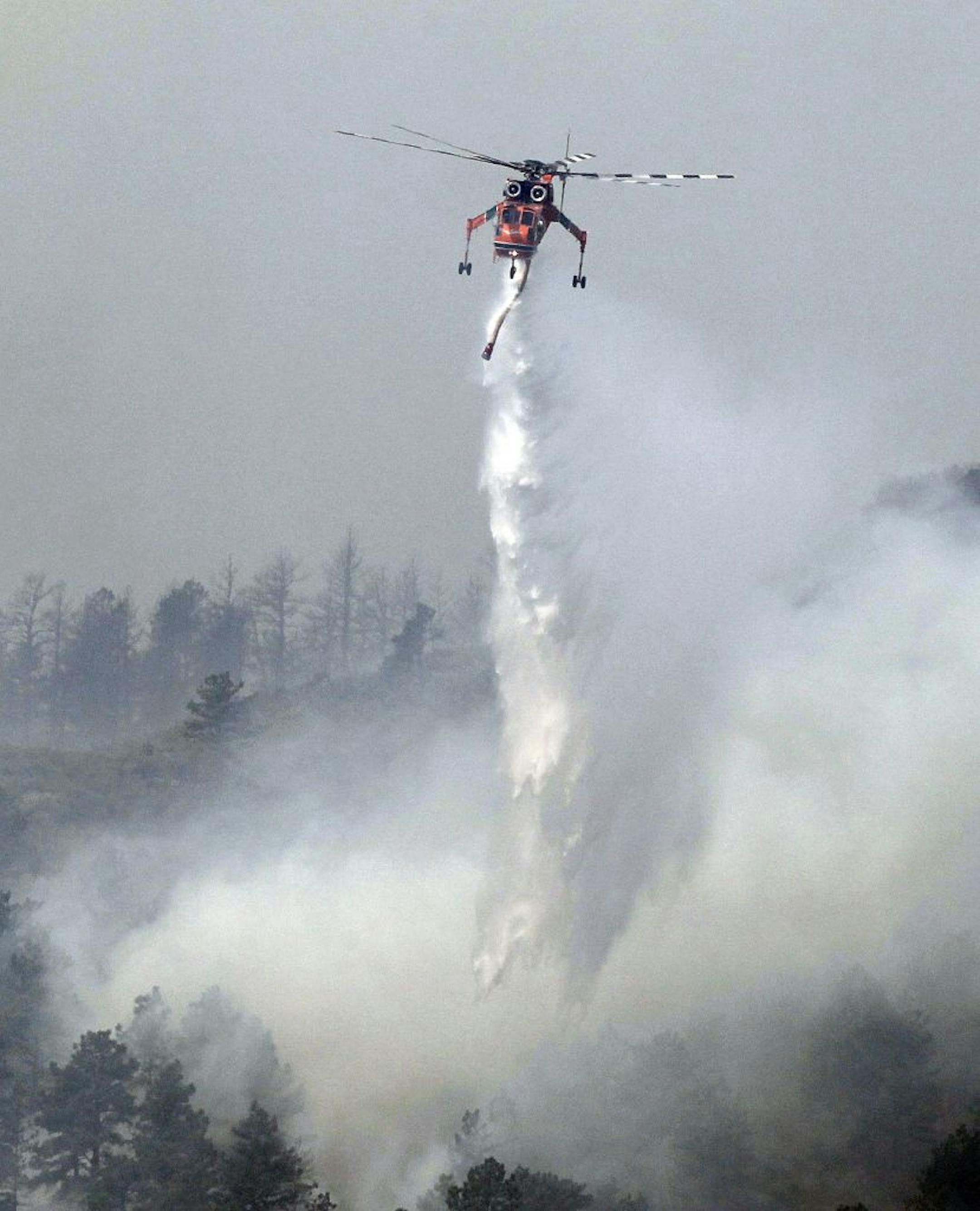 A helicopter makes a water drop on the High Park wildfire near Fort Collins, Colo., on Monday, June 11, 2012. The wildfire is burning out of control in northern Colorado, while an unchecked blaze choked a small community in southern New Mexico as authorities in both regions battled fires Monday.