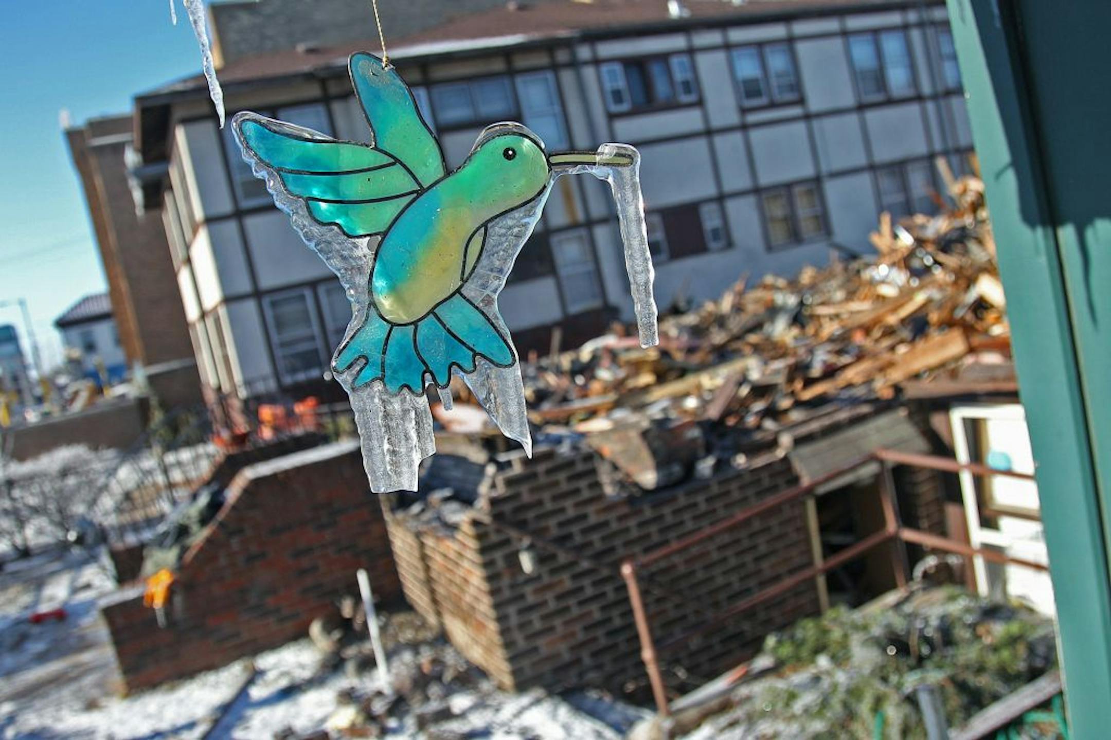 The remains of an apartment fire sat behind a bird chime that swung in the open air with icicles on it from the water used to put out the fire.
