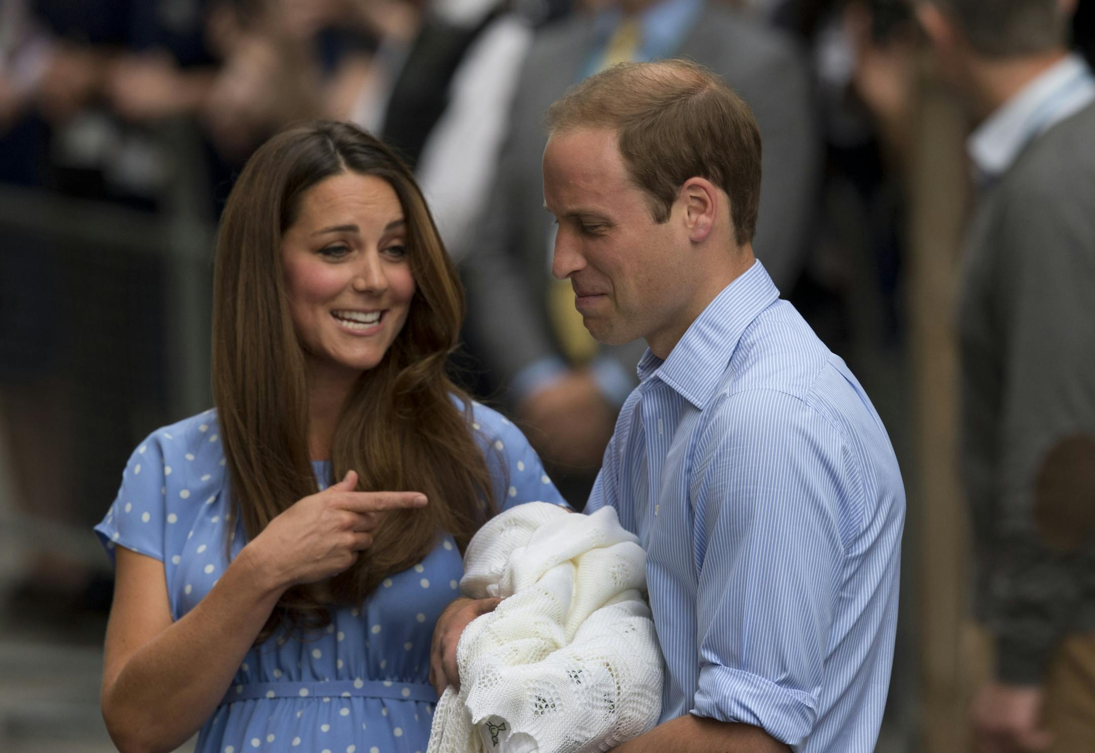 Britain's Prince William and Kate, Duchess of Cambridge react as they talk to the media while holding the Prince of Cambridge.