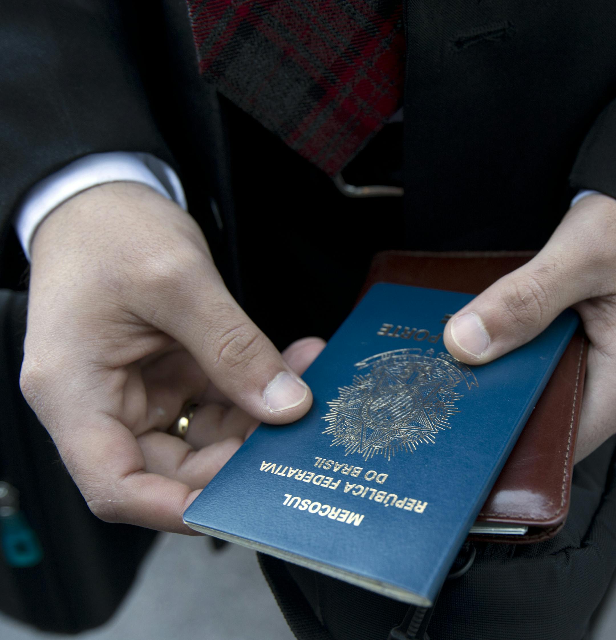 Filipe Diniz, who traveled from Brazil, readies his passport he'll use to claim his ticket before opening session of a two-day Mormon church conference Saturday, Oct. 4, 2014, in Salt Lake City. In addition to those filling up the 21,000-seat conference center during the sessions, thousands more listen or watch around the world in 95 languages on television, radio, satellite and Internet broadcasts. (AP Photo/Kim Raff)