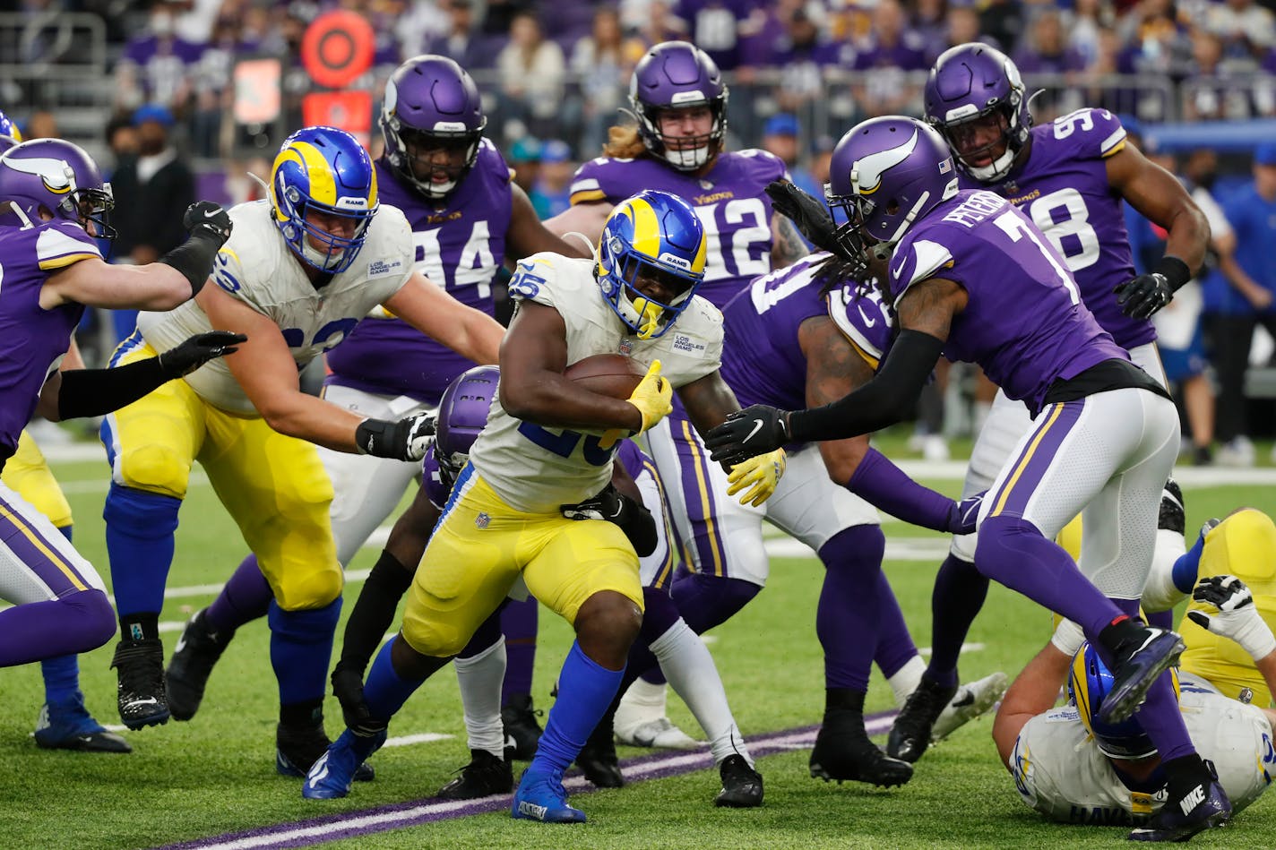 Los Angeles Rams running back Sony Michel (25) runs from Minnesota Vikings defenders during the first half of an NFL football game, Sunday, Dec. 26, 2021, in Minneapolis. (AP Photo/Bruce Kluckhohn)