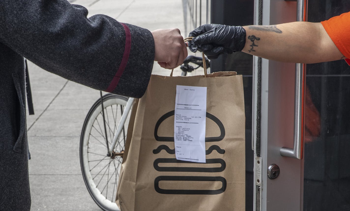 An order is handed of for delivery at a Shake Shack in New York, Monday, April 20, 2020. Shake Shack, the fast-food chain, said on Sunday that it was returning a $10 million loan from a federal program to help small businesses, following criticism that the stimulus program had favored large chains. (Brittainy Newman/The New York Times)