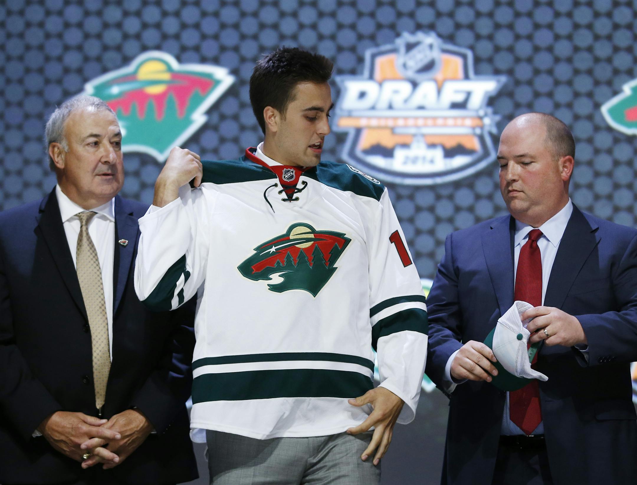 Alex Tuch pulls on a Minnesota Wild sweater after being chosen 18th overall during the first round of the NHL hockey draft, Friday, June 27, 2014, in Philadelphia. (AP Photo/Matt Slocum)