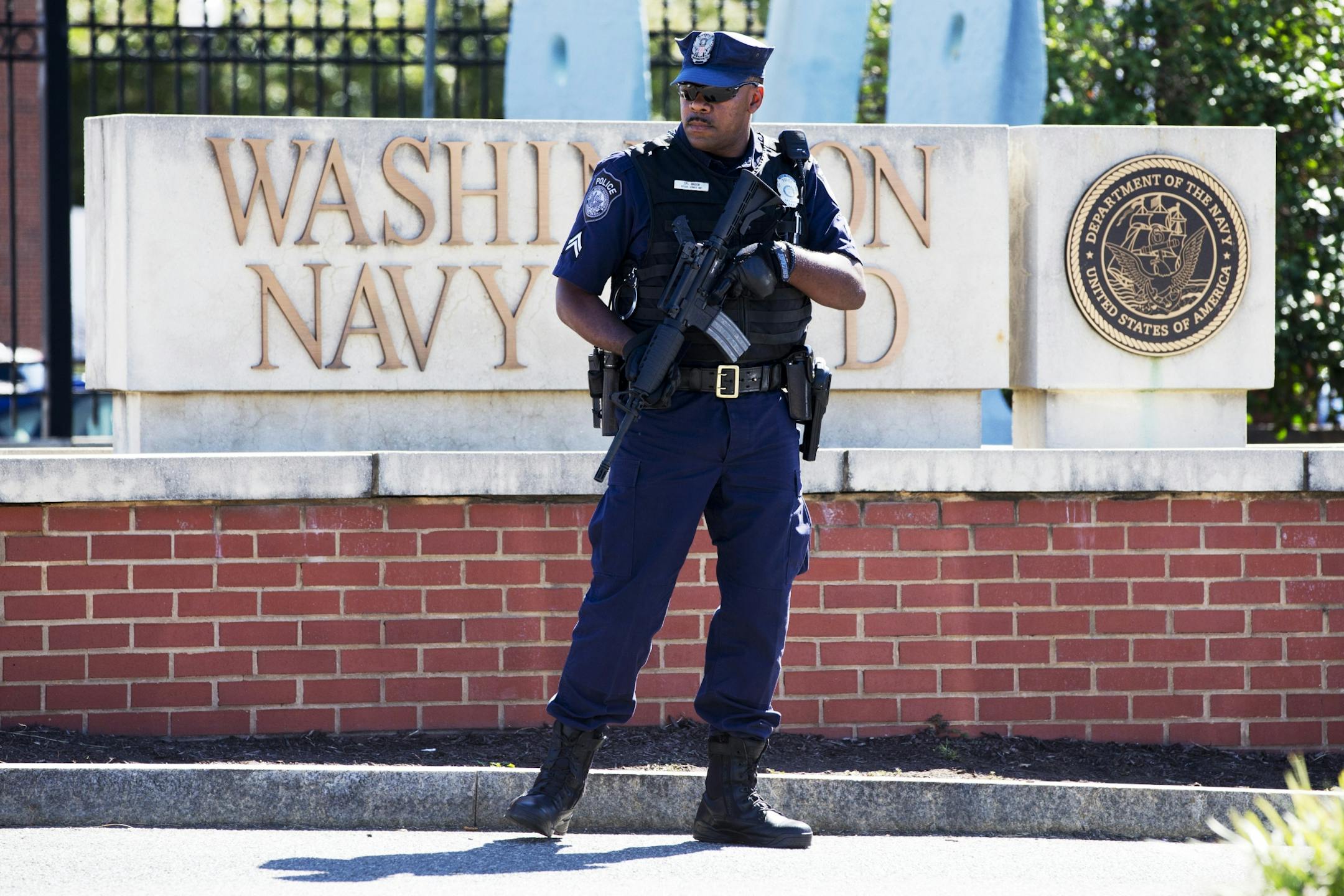 An armed officer who said he is with the Department of Defense, works near the gate at the Washington Navy Yard, closed to all but essential personnel, in Washington, on Tuesday, Sept. 17, 2013, the day after a gunman launched an attack inside.