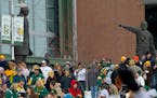 Green Bay Packers fans stand near statues of Vince Lombardi, left, and Curly Lambeau in 2011