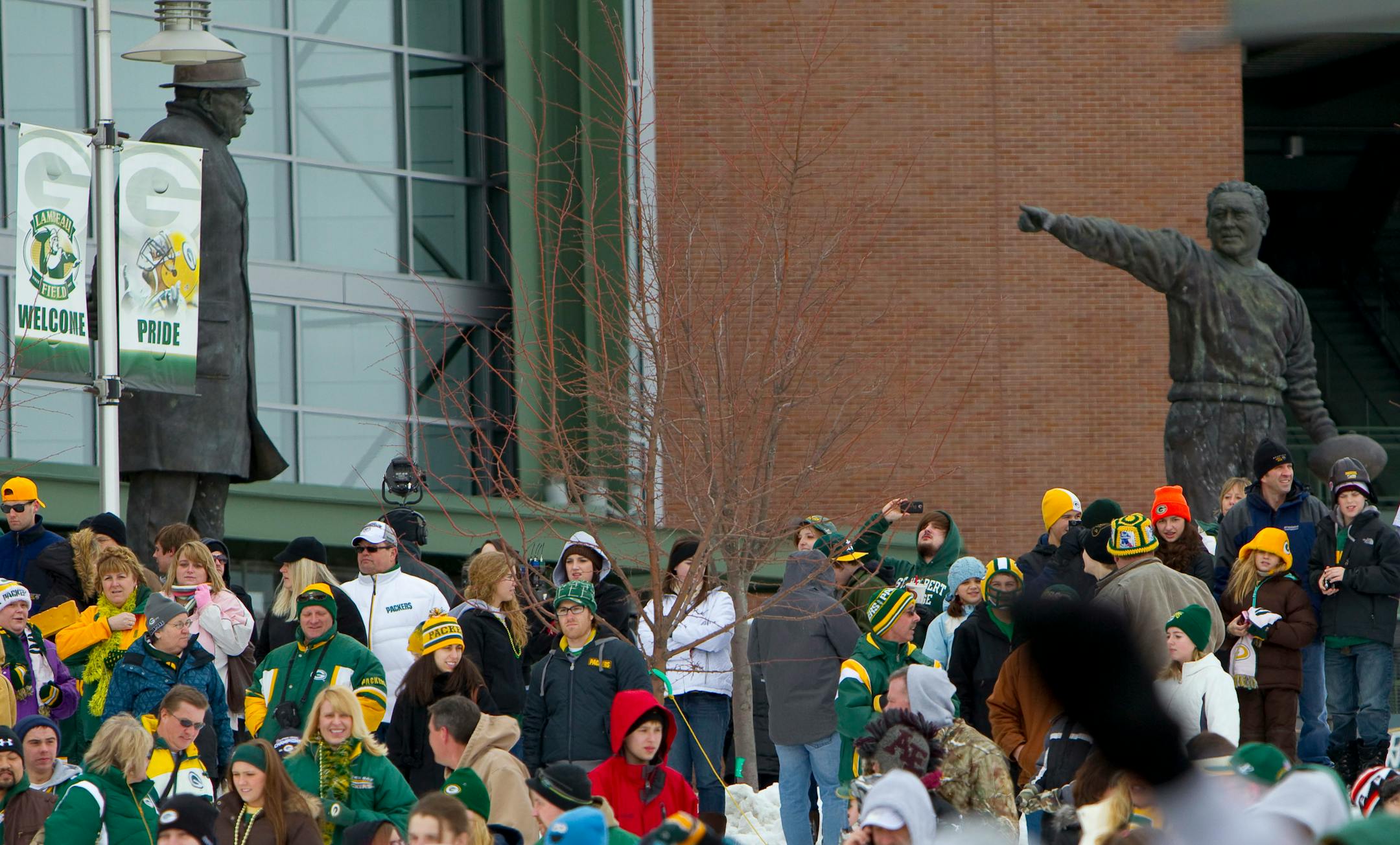Green Bay Packers fans stand near statues of Vince Lombardi, left, and Curly Lambeau in 2011