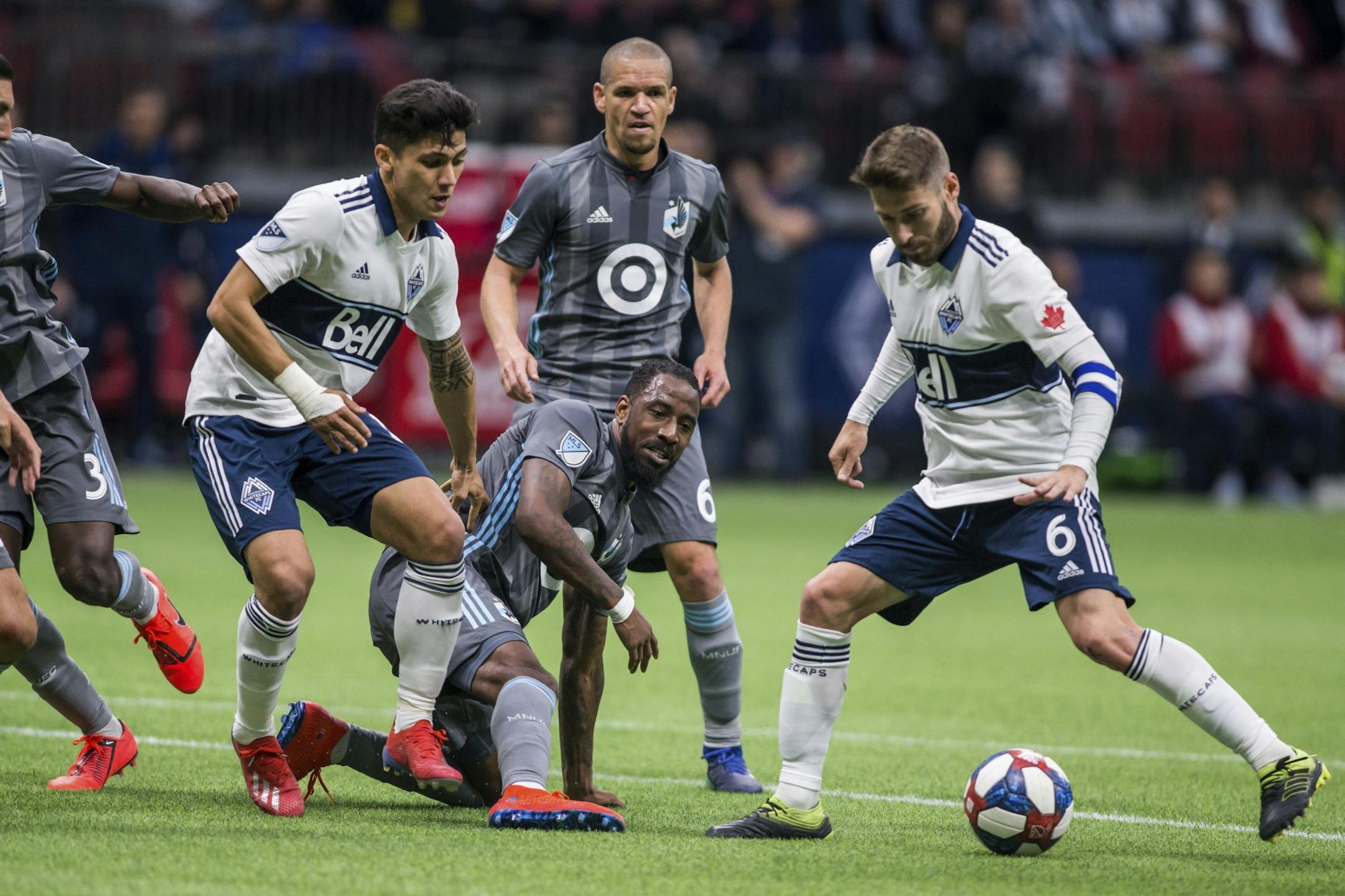 Vancouver Whitecaps' Jon Erice (6) plays the ball as teammate Fredy Montero (12) and Minnesota United's Ike Opara (3) watch during the second half of an MLS soccer match Saturday, March 2, 2019, in Vancouver, British Columbia.
