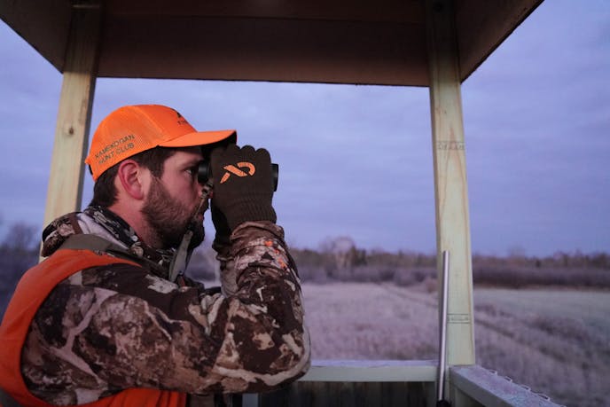 Travis Pennings uses a pair of binoculars to look for deer in the early morning hours, Nov. 3, 2018, during opening weekend of the season in Sandstone, Minn.