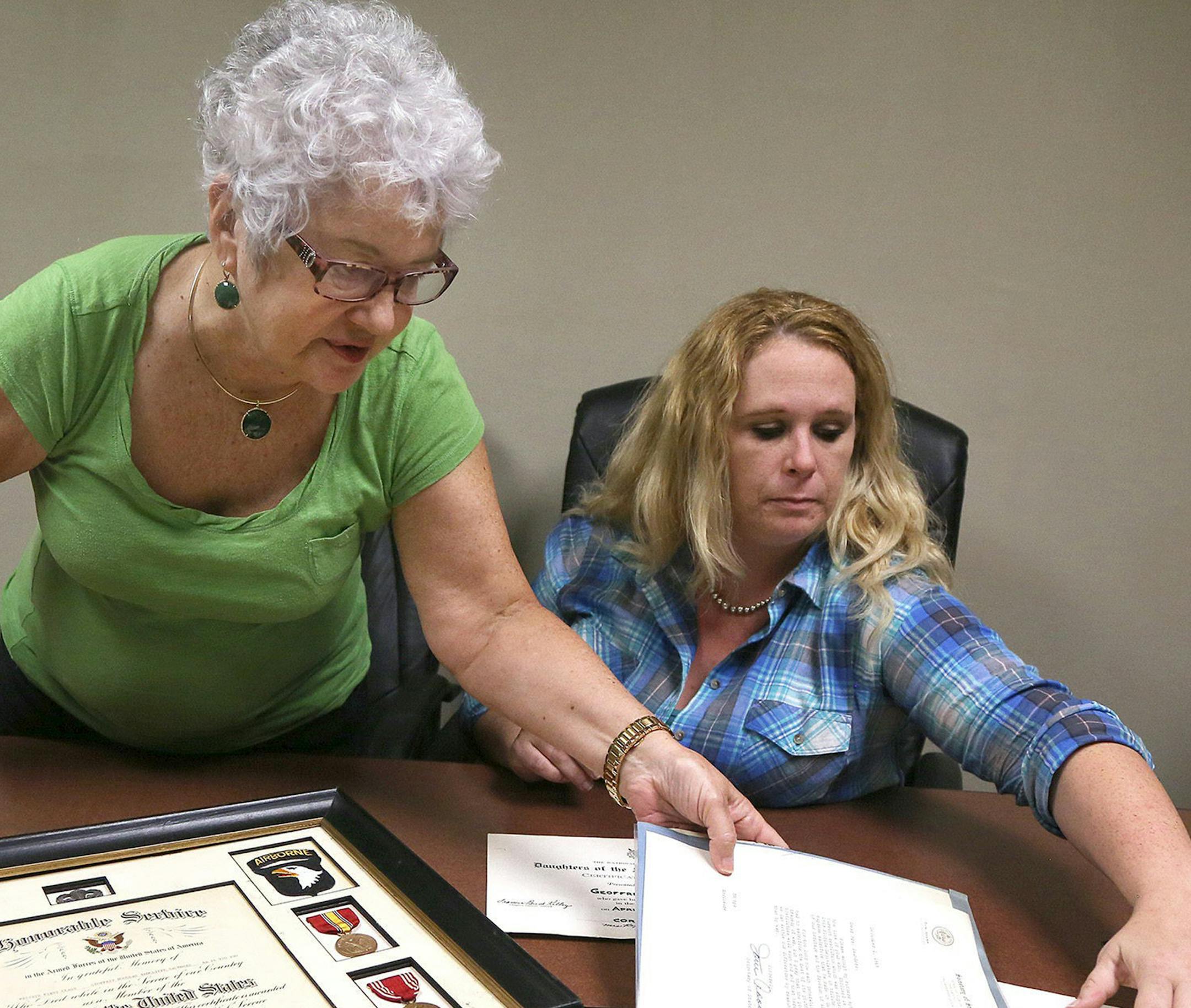 Darlene Stosik, left, of Pembroke Pines, Fla., looks over military medals and letters belonging to her brother Private Geoffrey Saunders, who died in Vietnam in 1968. At right is Meghan Burns of Coral Springs, Fla., who found the military medals in an abandoned suitcase in her attic while moving. (Carline Jean/Sun Sentinel/TNS)