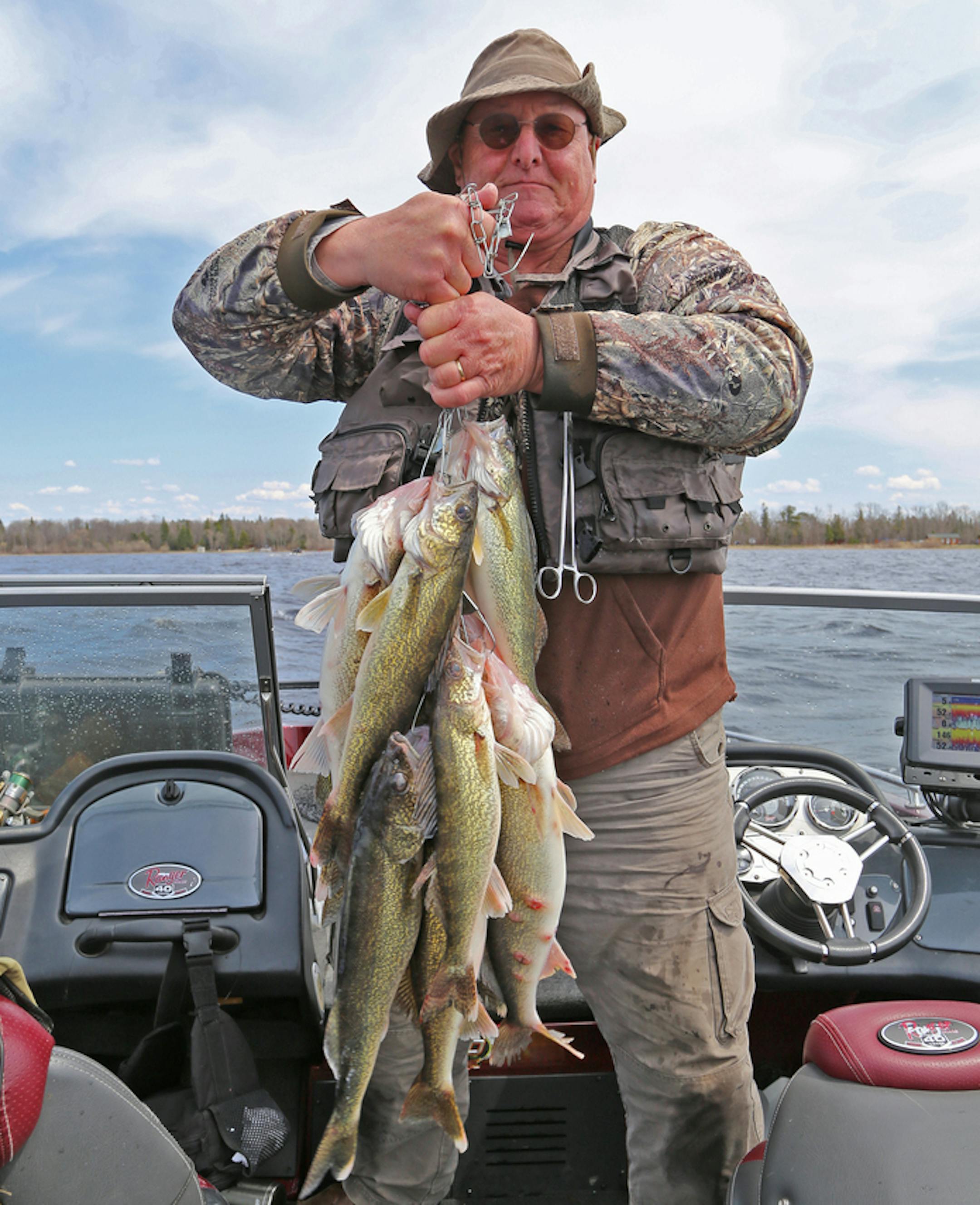 John Weyrauch of Stillwater hoists a three-person limit of 12 Upper Red Lake walleyes caught Saturday on the opening day of fishing. Winds tossed boats around on the big lake. Fishing was good, but perhaps somewhat slower than last year's stellar opener. ORG XMIT: MIN1905111545454954
