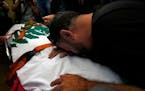 A friend of Reuters videographer Issam Abdallah who was killed by Israeli shelling mourns over his body during his funeral procession in his hometown 