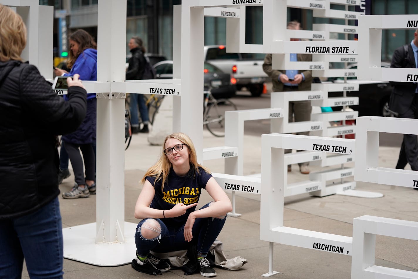 Mary Rolfes of Elk River poses for a sad photo in front of the Michigan bracket at the Tip-Off Tailgate on Nicollet Mall. ] LEILA NAVIDI • leila.navidi@startribune.com BACKGROUND INFORMATION: Final Four fans gather at the Tip-Off Tailgate party on Nicollet Mall on Friday, April 5, 2019.