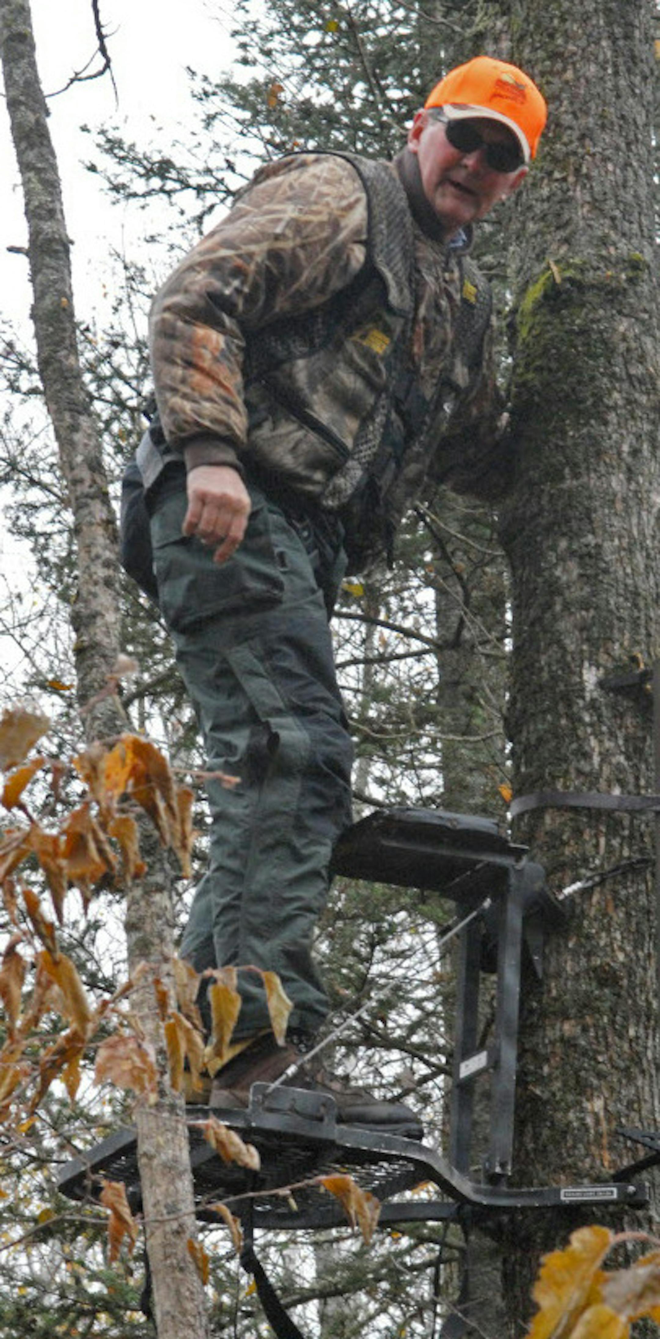 Once a portabe stand is placed, Dennis Anderson checks it for stability while holding onto the tree. His safety vest is also tethered to the tree above the stand. ORG XMIT: MIN2014091214033169