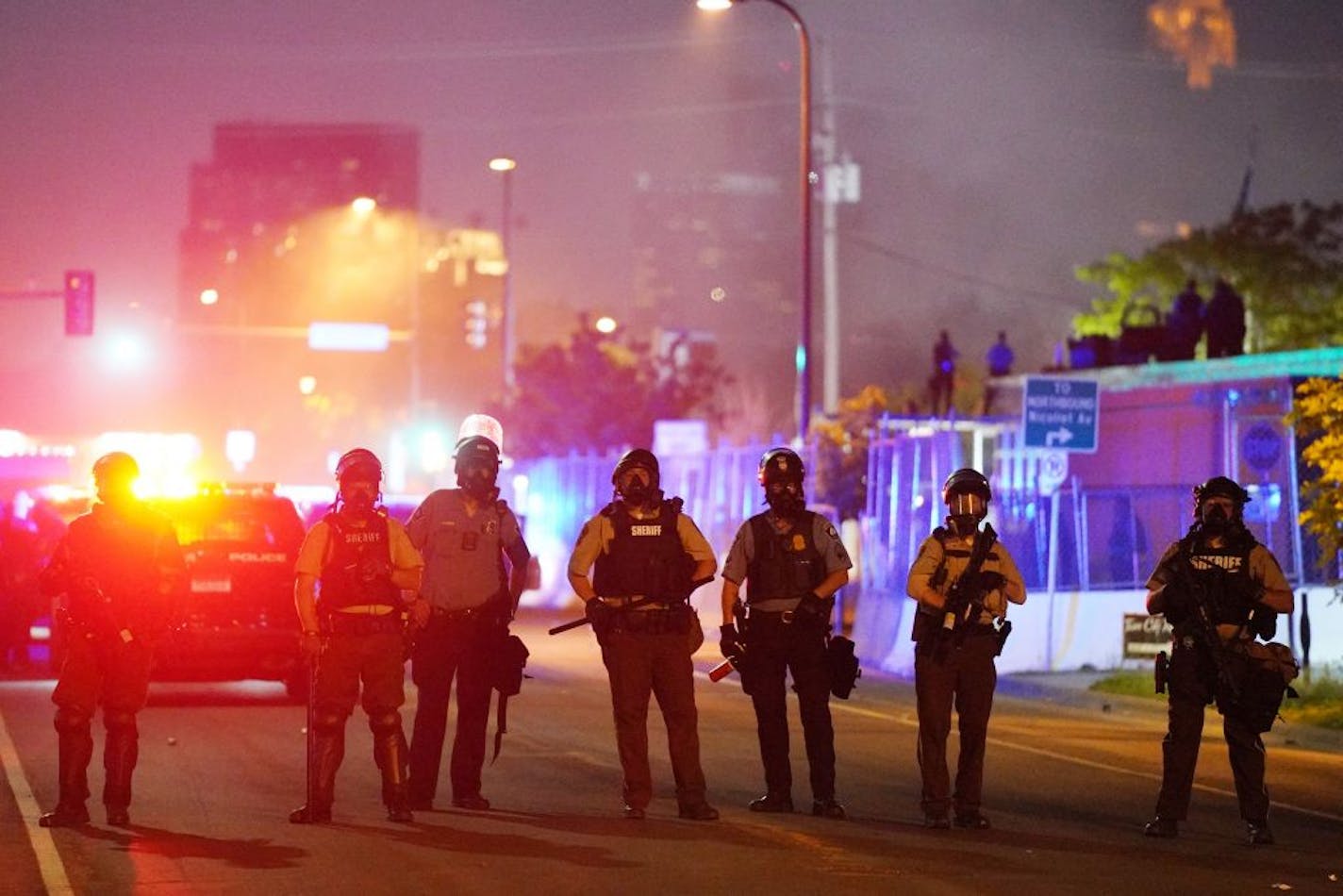 Police stood guard after using tear gas to clear a group of hundreds of protesters that had gathered near the Minneapolis Police 5th Precinct in the hour after curfew Saturday.