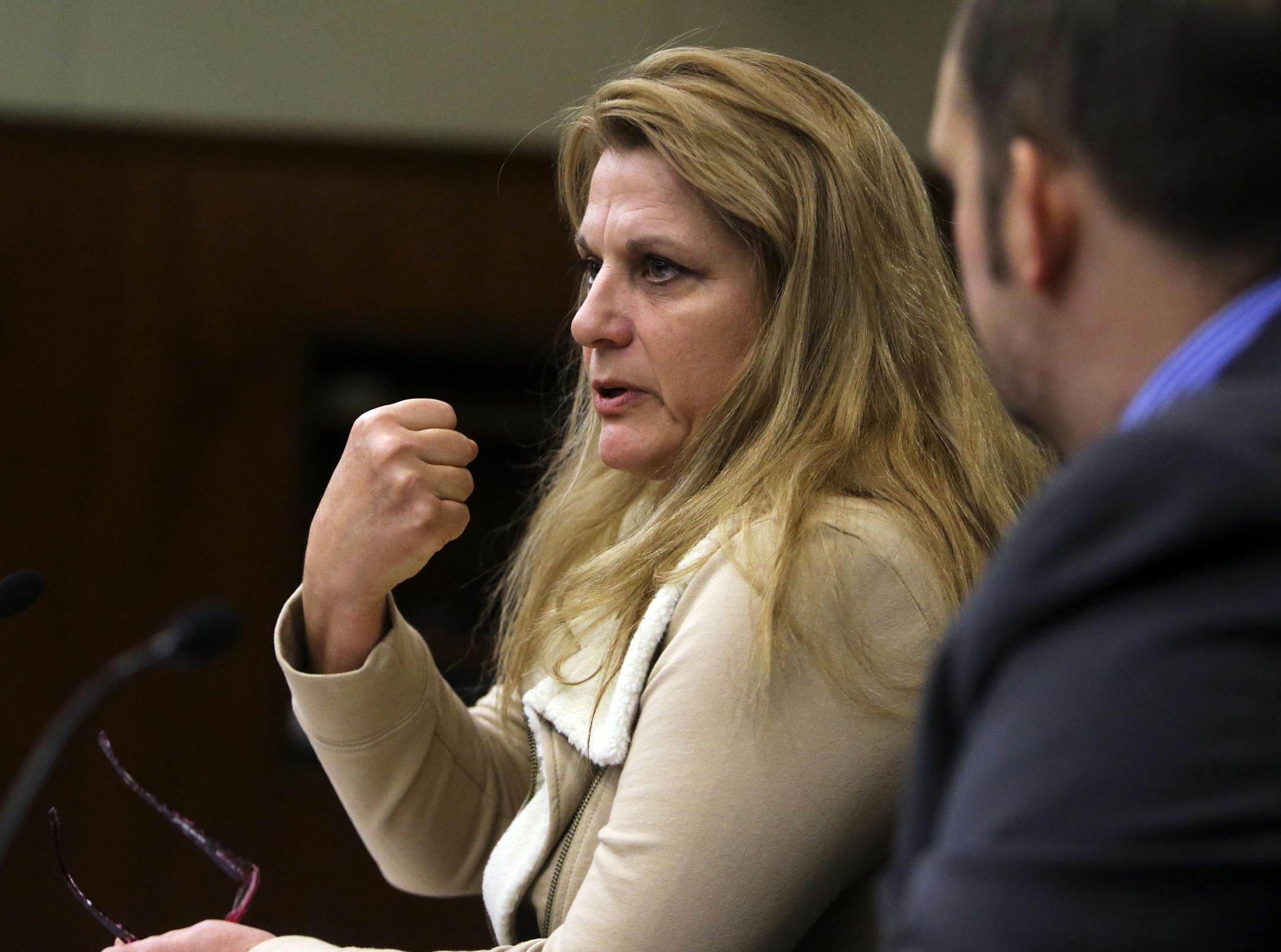 Domestic abuse victim Julie Zappa shows how her former abuser would clench his fist before striking her while speaking before the committee Tuesday, March 25, 2014, at the State Office Building in St. Paul, MN. Zappa said that while she supported the rights of domestic abuse victims she didn't believe it should infringe on the 2nd amendment and the rights of citizens to own and possess guns. Rep. Seated to her right is Rep. Dan Schoen (DFL), author of the bill.](DAVID JOLES/STARTRIBUNE) djoles@s