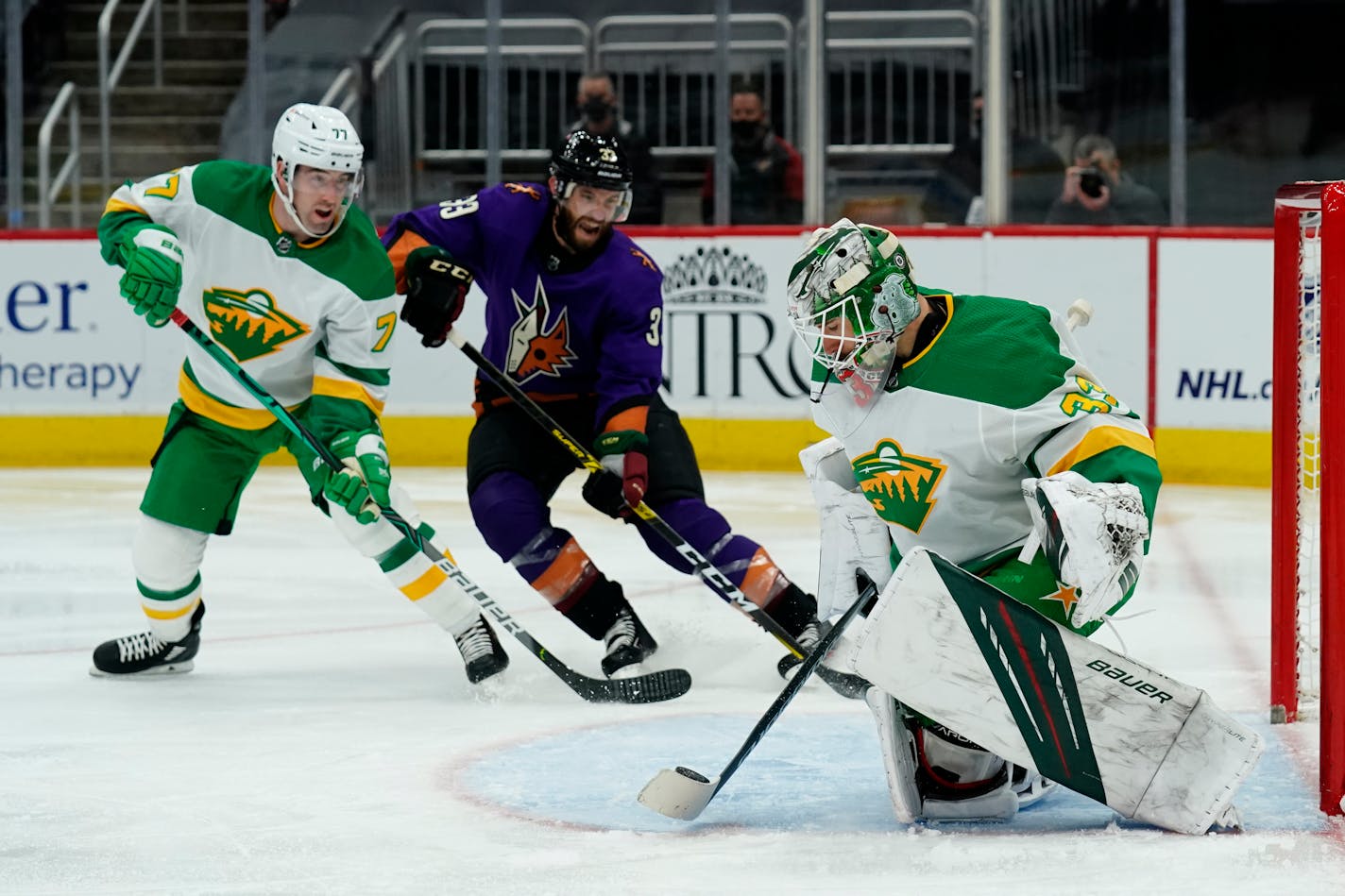 Minnesota Wild goaltender Cam Talbot (33) makes a save in front of Arizona Coyotes defenseman Alex Goligoski (33) as Wild defenseman Brad Hunt (77) defends in the second period during an NHL hockey game, Saturday, March 6, 2021, in Glendale, Ariz. (AP Photo/Rick Scuteri)