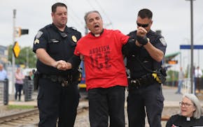 Law enforcement officials take Rev. Daniel Romero of the First Congregational Church of Minnesota into custody after Romero and several other protesto