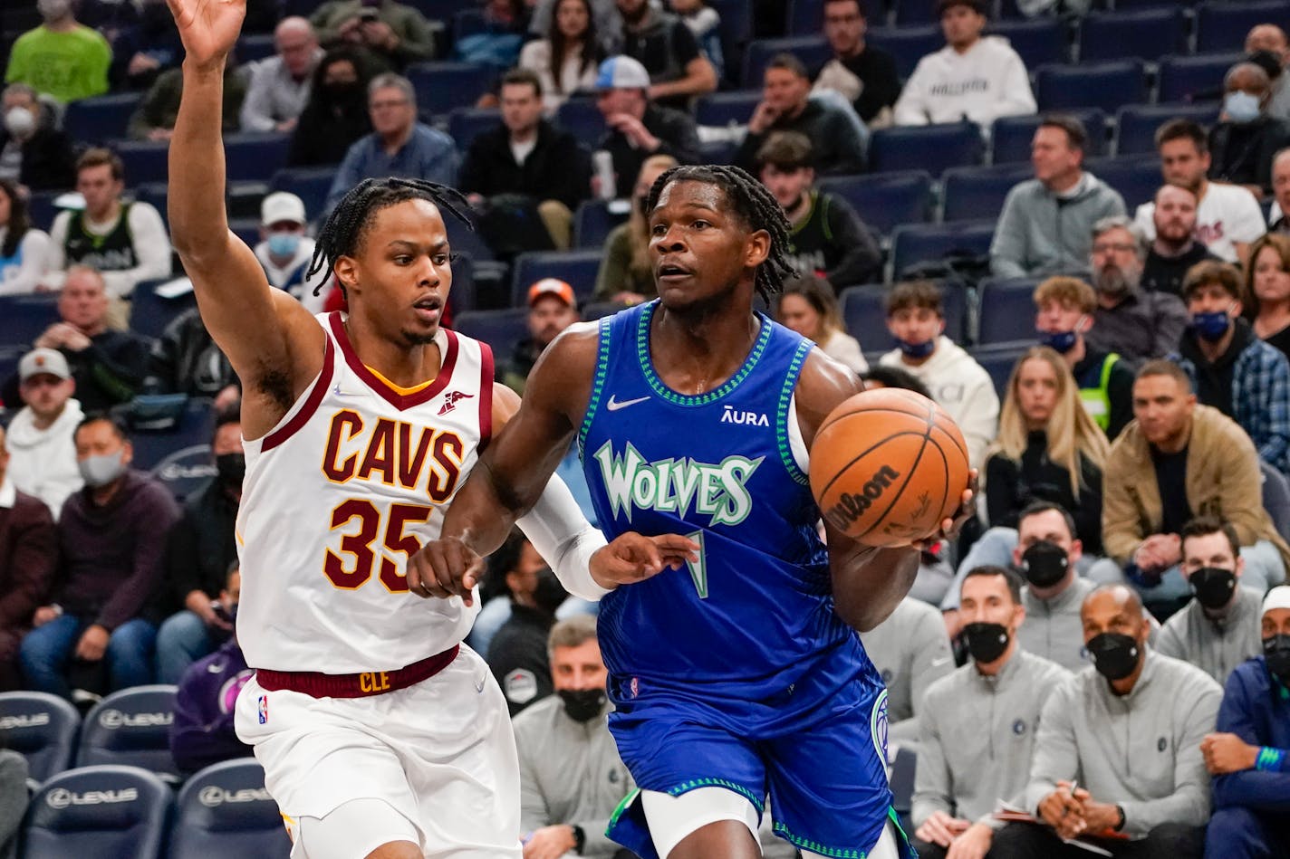 Minnesota Timberwolves guard Anthony Edwards, right, drives past Cleveland Cavaliers guard Isaac Okoro in the first half of an NBA basketball game Friday, Dec. 10, 2021, in Minneapolis. (AP Photo/Craig Lassig)