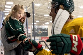 Fiona Vopat, 3, was held by her father Josh as she got a fist bump from Wild forward Adam Beckman on Thursday.