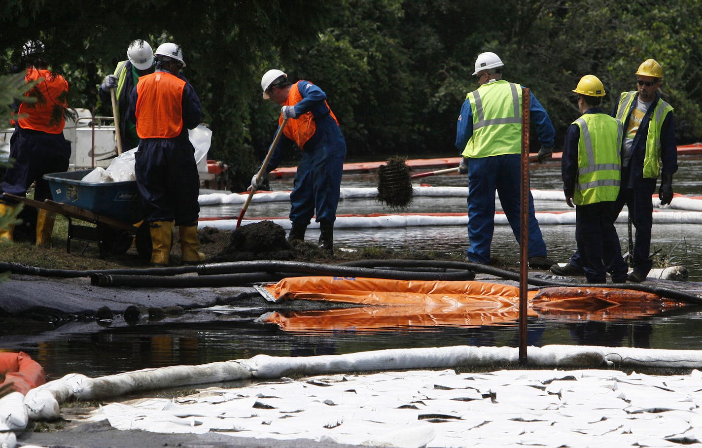 FILE - In this July 30, 2010 file photo, crews clean up oil, from a ruptured pipeline, owned by Enbridge Inc, near booms and absorbent materials where Talmadge Creek meets the Kalamazoo River as in Marshall Township, Mich. Federal investigators are expected to present their findings Tuesday, July 10, 2012 on the likely cause of a pipeline rupture that spilled more than 800,000 gallons of crude oil into the river nearly two years ago. (AP Photo/Paul Sancya, File) ORG XMIT: MIPS102