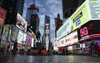 FILE - This March 20, 2020 file photo, shows a screen displaying messages concerning COVID-19, right, in a sparsely populated Times Square in New York