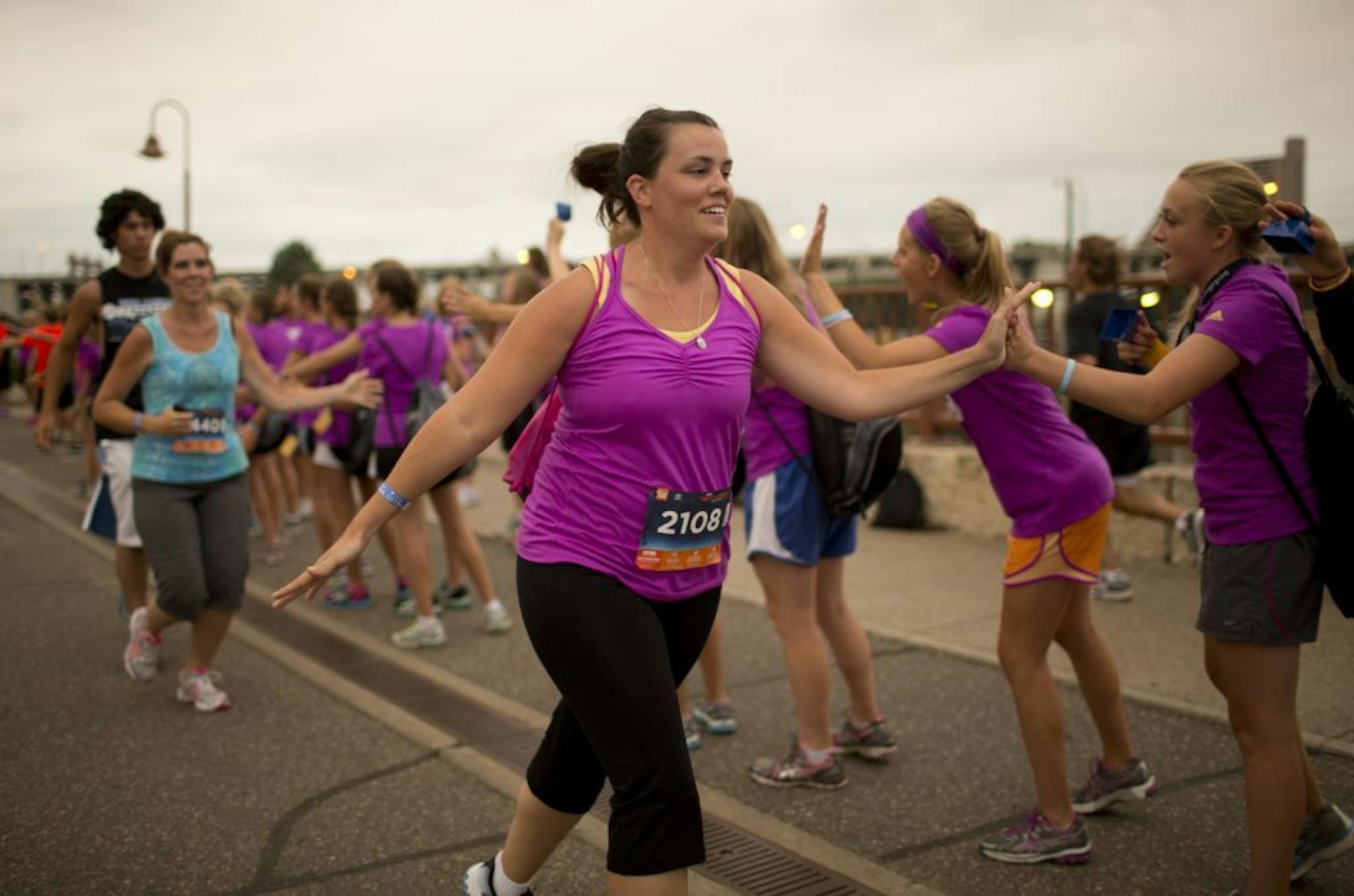Thousands of participants in the Minneapolis Aquatennial's Life Time Torchlight 5K Wednesday night, July 18. 2012 didn't let the heat stop them from running the race. These runners were just stepping onto the Stone Arch Bridge for the home stretch as they were cheered on by school age attendees of Olympian Carrie Tollefson's 2012 Training Camp for young runners.