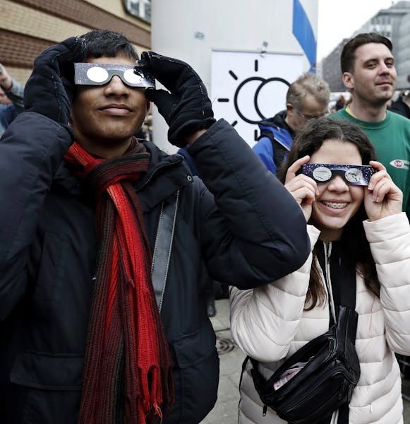 People follow the solar eclipse, viewed through special glasses from the planetarium in Copenhagen Friday March 20, 2014. (AP/Photo: Jens Dresling/POL