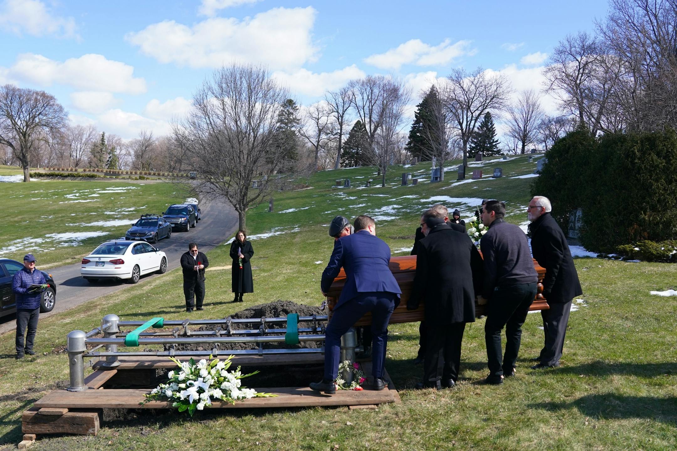 Pallbearers placed the casket of Elie Farhat who recently died of COVID-19 at the age of 92, over his gravesite Thursday.