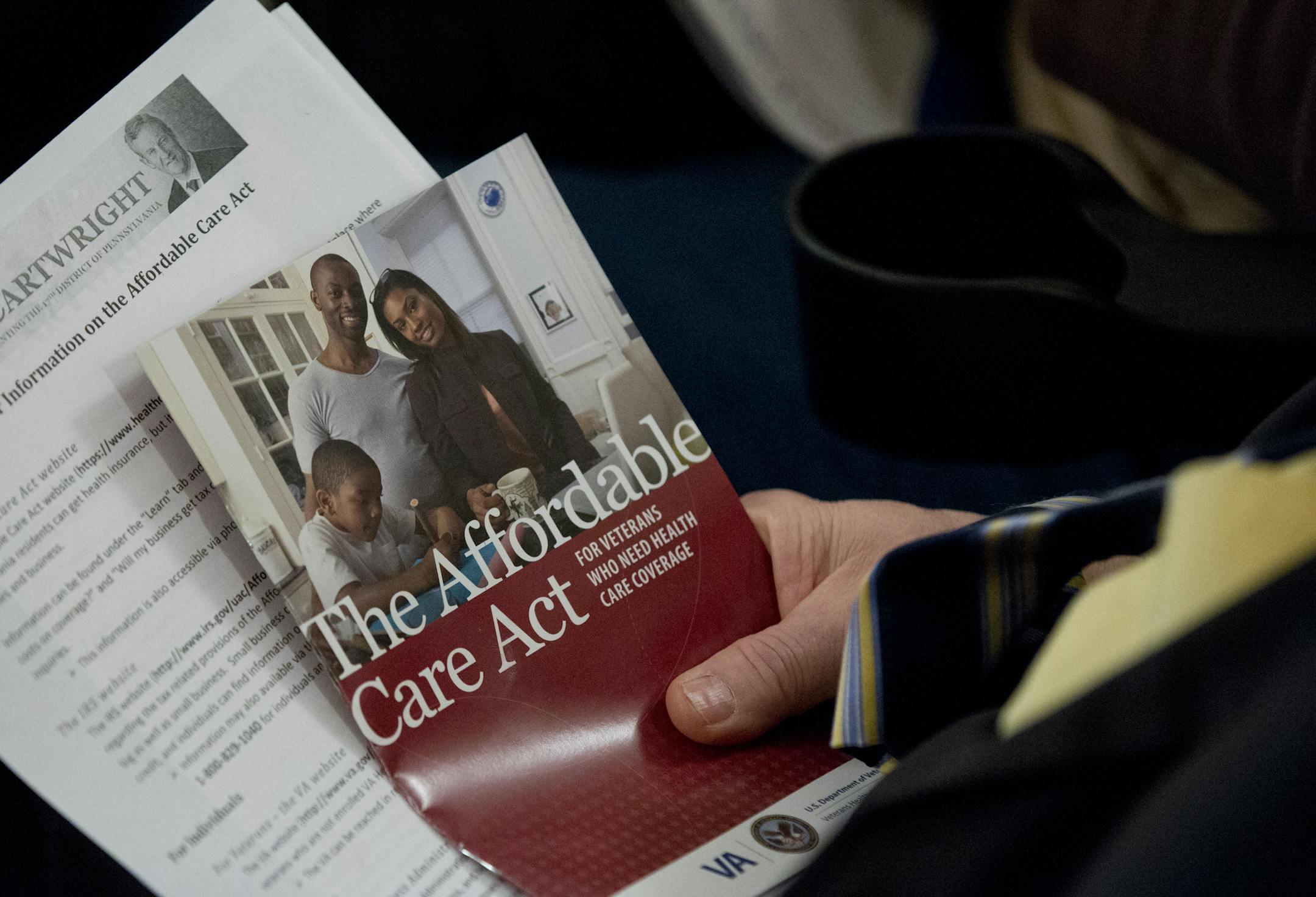 An audience member holds a pan flit as he listens during an federal health care law informational town hall meeting.