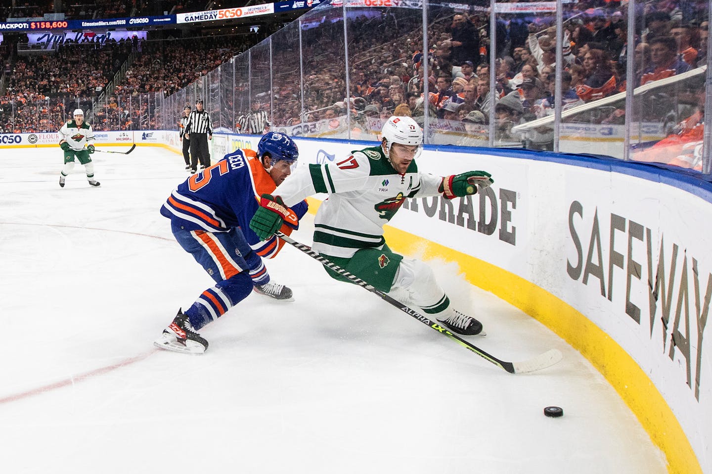 Minnesota Wild's Marcus Foligno (17) and Edmonton Oilers' Cody Ceci (5) battle for the puck during first-period NHL hockey game action in Edmonton, Alberta, Friday, Dec. 9, 2022. (Jason Franson/The Canadian Press via AP)