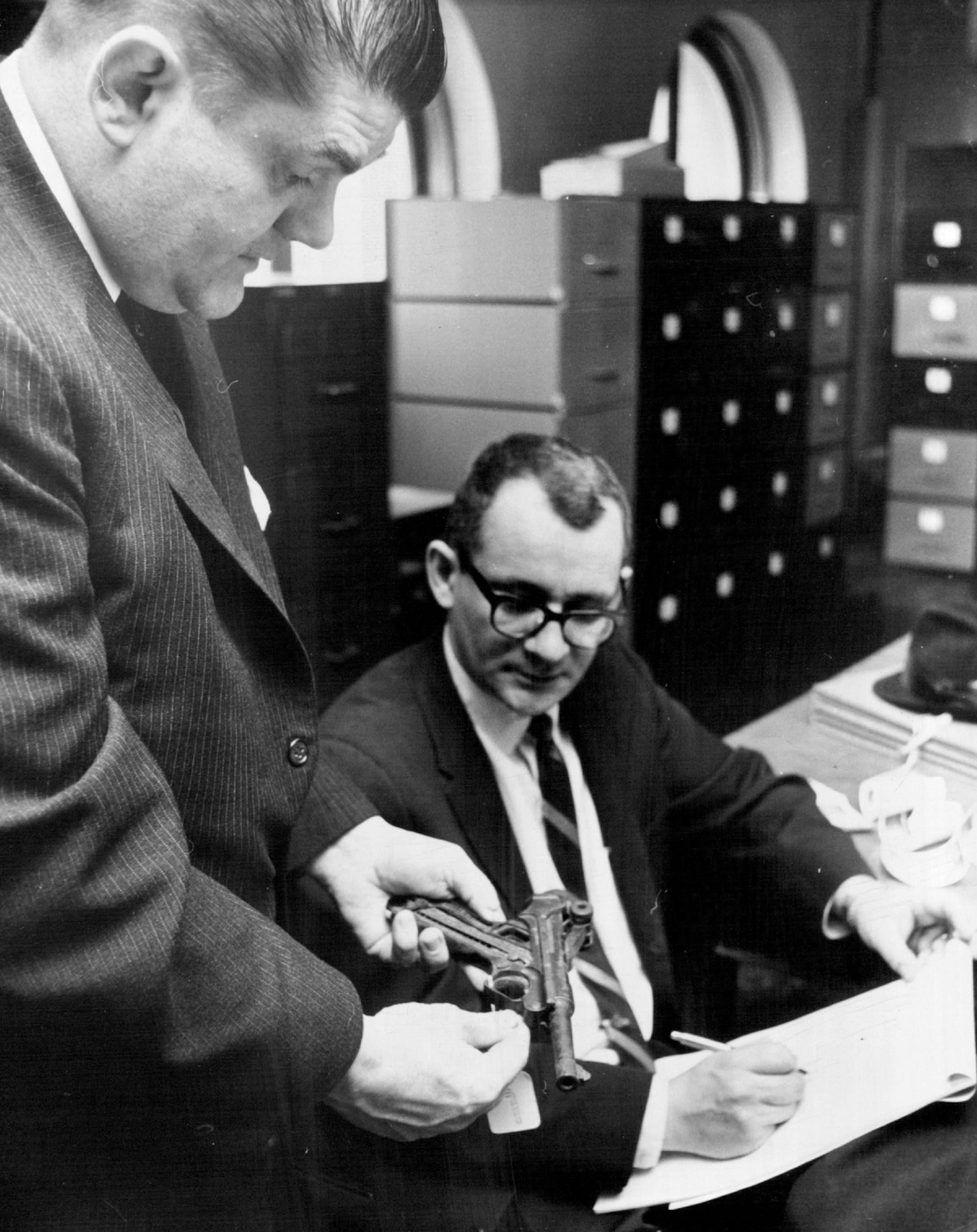 February 12, 1964 Murder Weapon -- Attorneys for Norman J. Mastrian Tuesday inspected the evidence in the T. Eugene Thompson trial. Looking at the material in the Hennepin County clerk of court's office, John A. Cochrane showed his partner, Douglas Thomson, the Luger used to beat Mrs. Thompson to death. The two St. Paul lawyers will defend Mastrian in his first degree murder trial that begins Monday in Duluth, Minn. Mastrian is accused of acting as the middleman in the alleged murder-for-hire. F