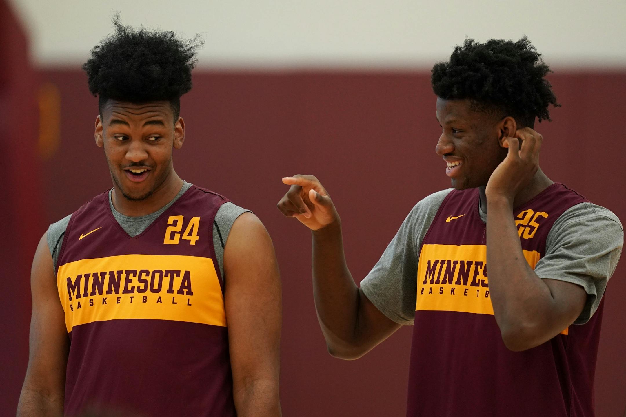 Gophers forward Eric Curry (24) joked with center Daniel Oturu (25) during Thursday's practice.