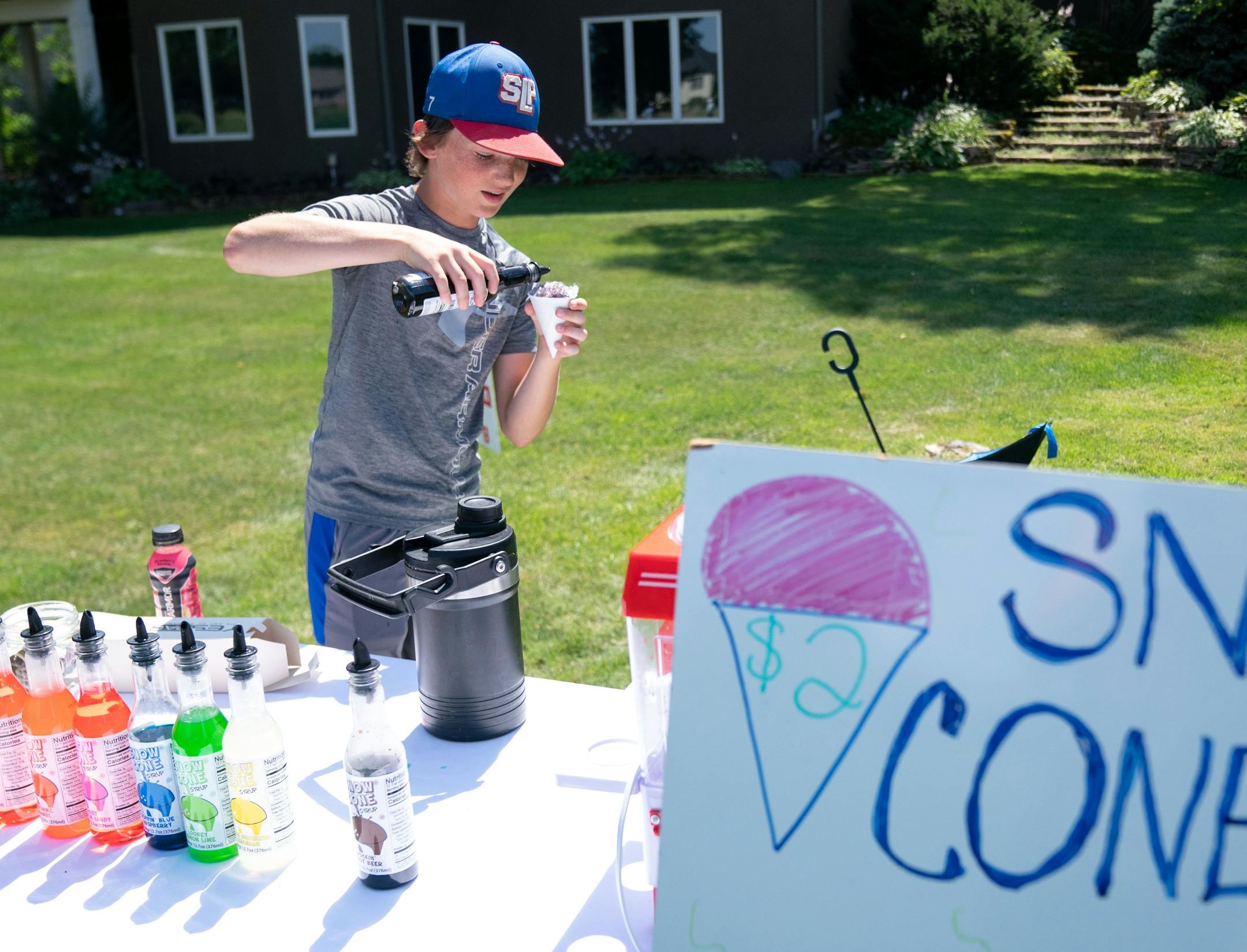 Austin Finkelson, 13, of Blaine, Minn. sells snow cones to golf spectators from the backyard of a neighboring residence during the 3M Open.