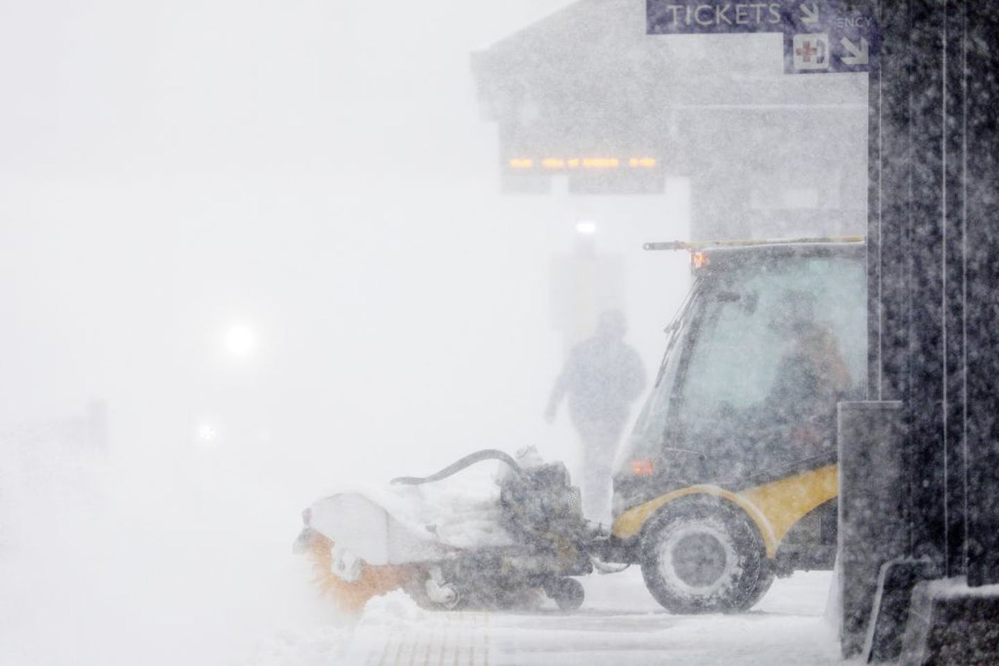 A worker tried to clear snow and ice from the Government Center Plaza light-rail station in downtown Minneapolis on Saturday. Blizzard conditions in the Twin Cities are making travel dangerous and shutting down the metro area, including the airport.