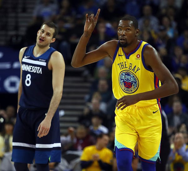 The Warriors' Kevin Durant, right, celebrated a basket as Wolves forward Nemanja Bjelica looked on with dismay in the first half.