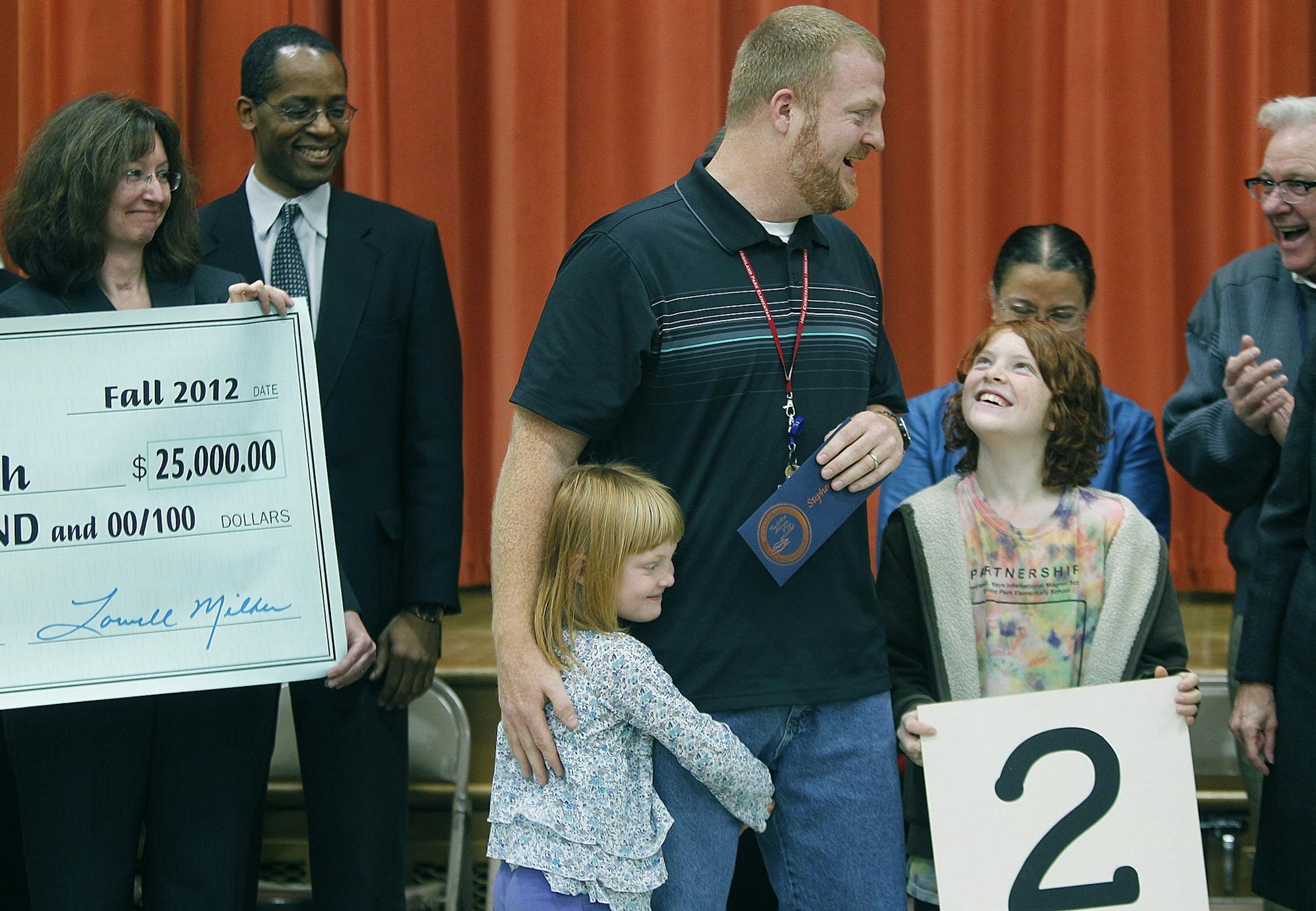 Highland Park Elementary music teacher Steve Abenth was surrounded by his kids, Nora, 5, a kindergartener at the school, and Charlie, 9, a fourth-grader, after it was announced in a school assembly that he had won the $25,000 Milken Educator Award, Friday, November 9, 2012 in St. Paul.