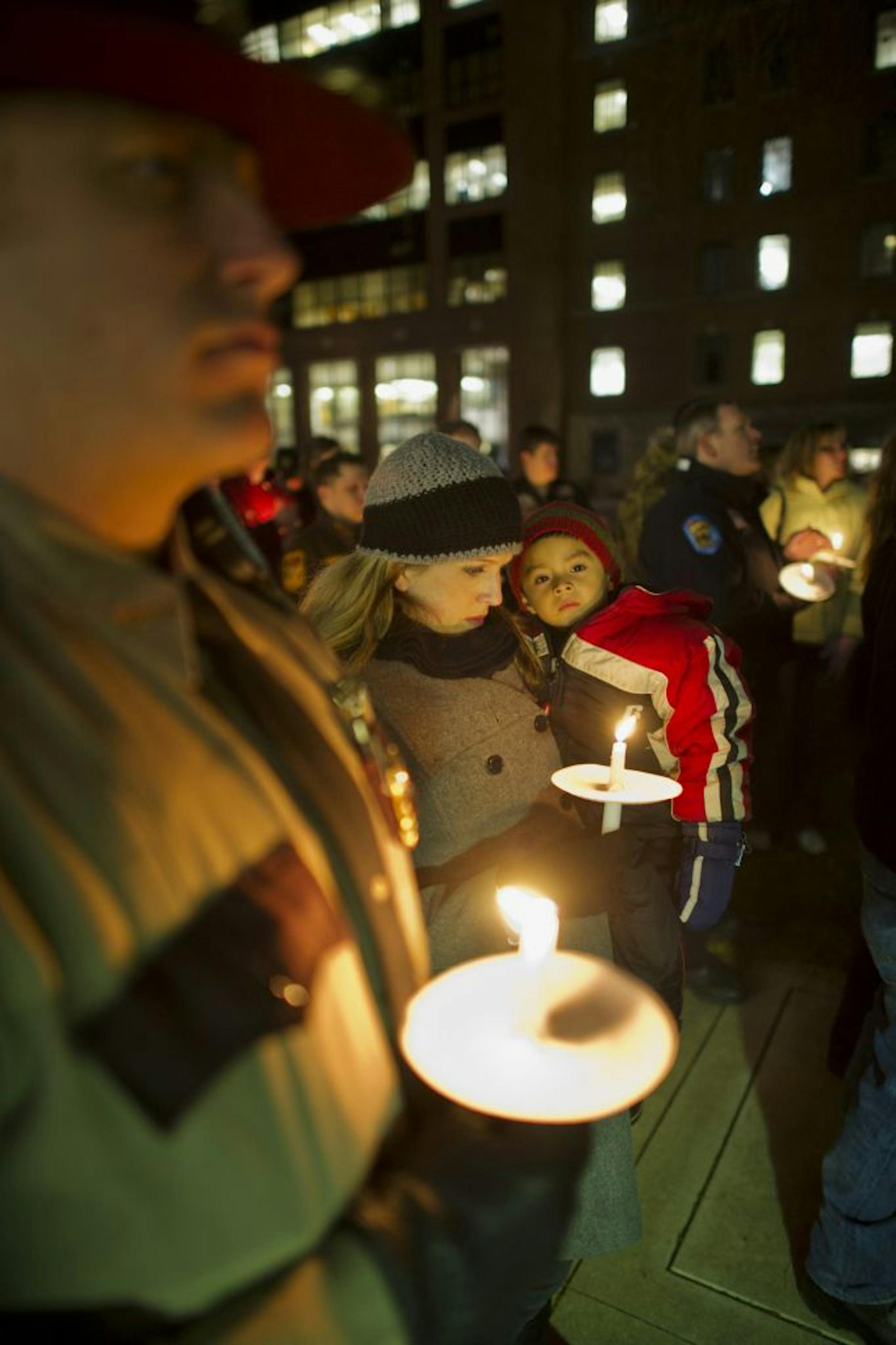 Law enforcement officers from several communities including Lake City and Rochester attended Tuesday night's vigil for officer Shawn Schneider at St. Marys. At left are State Patrol officer Lee Gear, his wife, Tiffany Gear, and their 4-year-old son, Jeremiah.