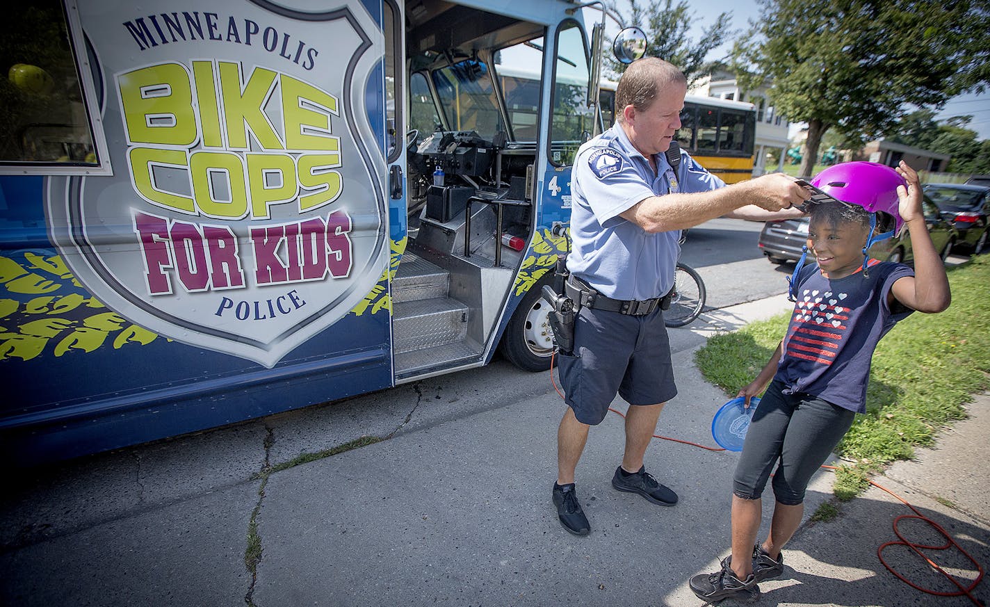 Minneapolis Police Officer Michael Kirchen was more than happy to pass along a free helmet to Jahnyra Lane, 10, cq, while she visited a community outreach BBQ, Thursday, August 24, 2017 in Minneapolis, MN. Bike Cops 4 Kids, a long-running community engagement program that helps at-risk kids, giving away bikes and equipment, hosting events and even showing up at murder scenes to show a different face of the department. ] ELIZABETH FLORES &#xef; liz.flores@startribune.com