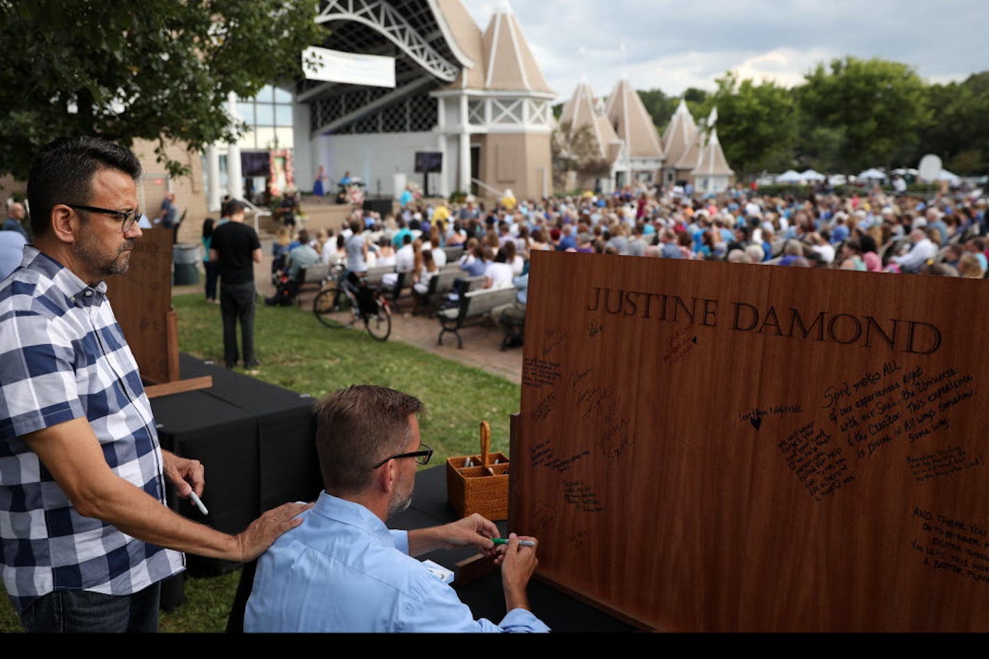 State Sen. Scott Dibble, DFL-Minneapolis, signed a wooden board for Justine Damond at Friday's memorial. With him was husband Richard Levy.