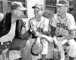 Lowell Ziemann (right) and catcher Edward Munson listen to coach Edor Nelson during Augsburg's 1957 season