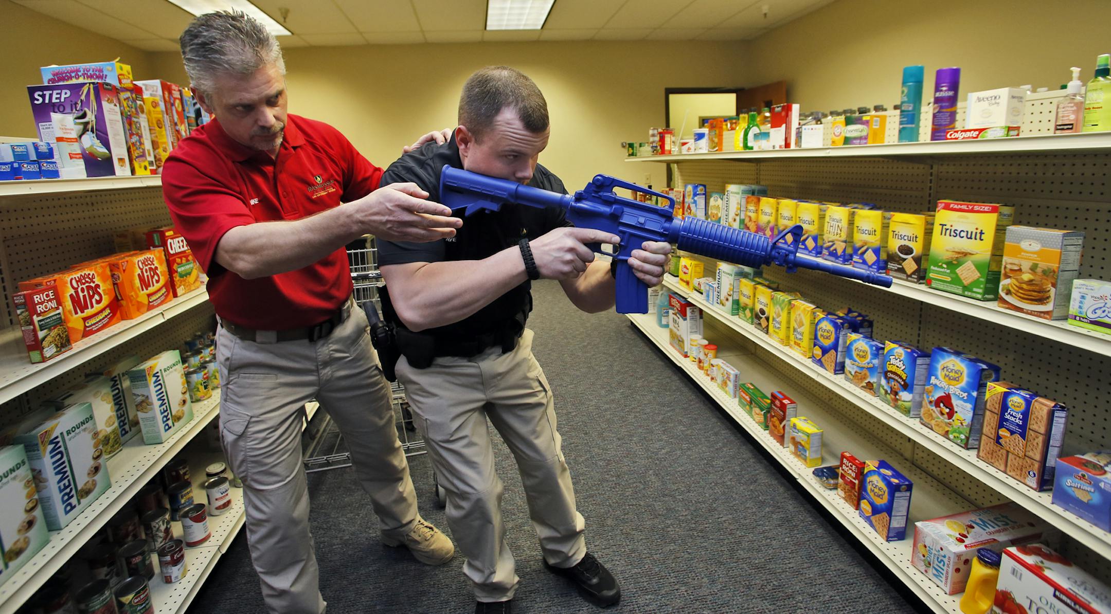 Rasmussen College in Eagan has opened a new police training facility with a number of scenario training rooms that depict situations police may find themselves in public encounters. Mike Ardolf, Law Enforcement Skills Coordinator, and Dave Eichman, law enforcement student, enact some of these situations. Ardolf, left, instructed Eichman how to react to a hostage or robbery situation as it may occur in a grocery store setting - one of the scenario trianing rooms at the college. (MARLIN LEVISON/ST